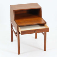 デンマーク製の北欧ビンテージサイドチェストです。チーク材の落ち着いた色合いと美しい木目が際立ち、奥行きをしっかりと確保した設計が実用性を高めています。上部はオープンスペースと、下段には小ぶりな引き出しを配置。真鍮調のつまみがさりげないアクセントとなり、直線的なフォルムとすらりとした脚部が軽やかな印象を与えます。ベッドサイドやリビングでの小物収納、簡易デスクとしても活躍し、経年による艶やかな風合いが空間に温もりを添える一台です。