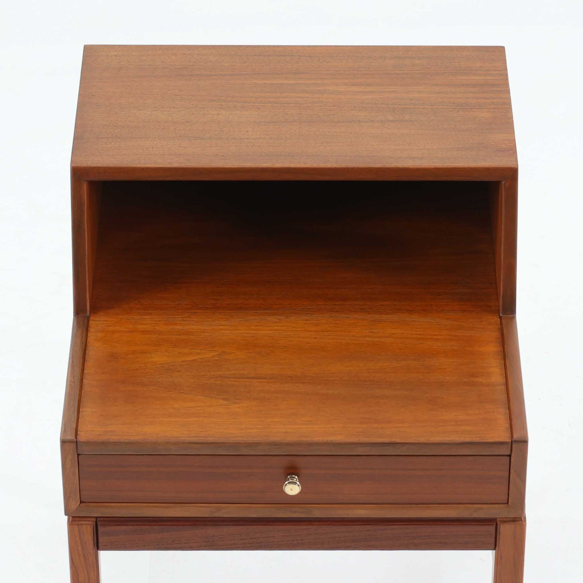 デンマーク製の北欧ビンテージサイドチェストです。チーク材の落ち着いた色合いと美しい木目が際立ち、奥行きをしっかりと確保した設計が実用性を高めています。上部はオープンスペースと、下段には小ぶりな引き出しを配置。真鍮調のつまみがさりげないアクセントとなり、直線的なフォルムとすらりとした脚部が軽やかな印象を与えます。ベッドサイドやリビングでの小物収納、簡易デスクとしても活躍し、経年による艶やかな風合いが空間に温もりを添える一台です。