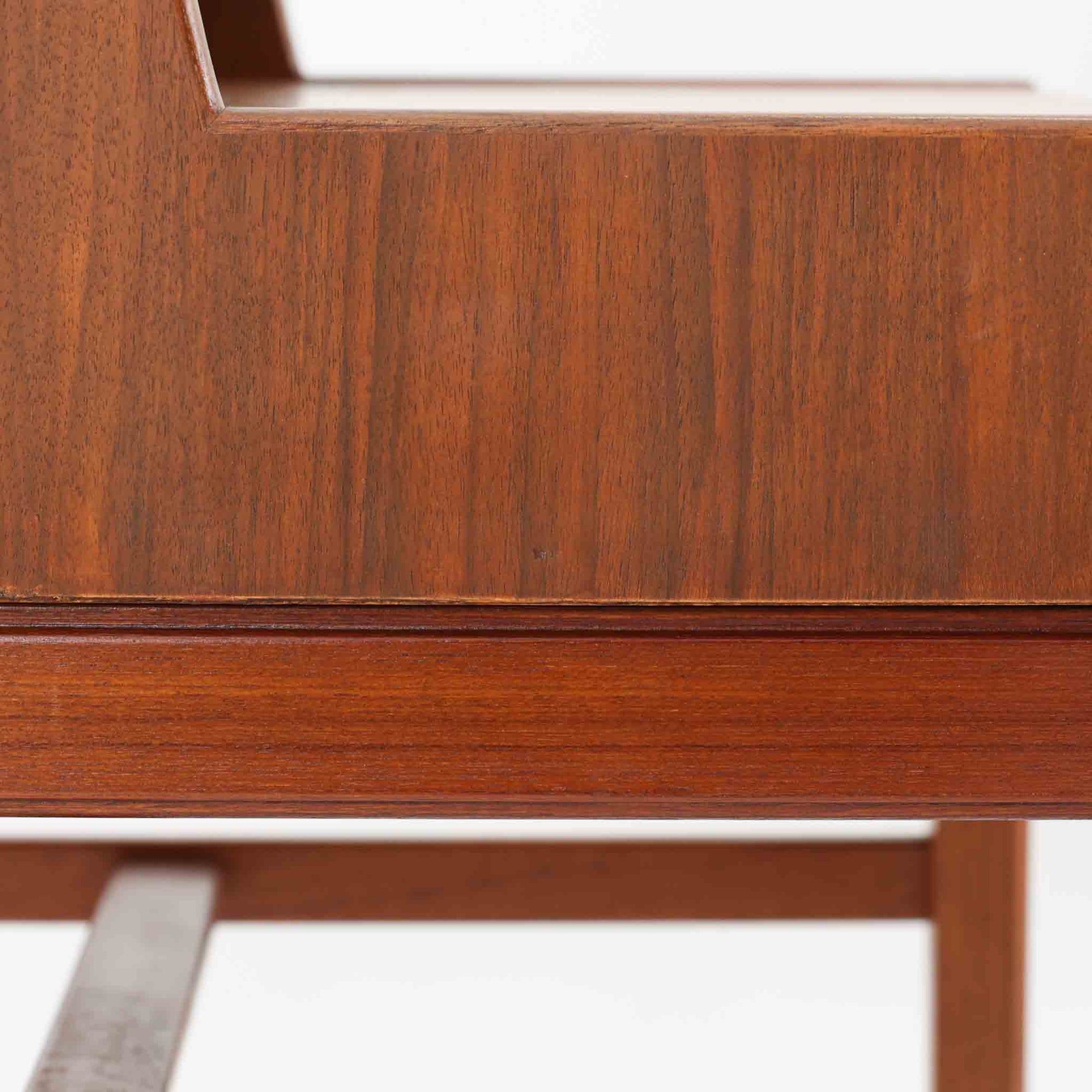 デンマーク製の北欧ビンテージサイドチェストです。チーク材の落ち着いた色合いと美しい木目が際立ち、奥行きをしっかりと確保した設計が実用性を高めています。上部はオープンスペースと、下段には小ぶりな引き出しを配置。真鍮調のつまみがさりげないアクセントとなり、直線的なフォルムとすらりとした脚部が軽やかな印象を与えます。ベッドサイドやリビングでの小物収納、簡易デスクとしても活躍し、経年による艶やかな風合いが空間に温もりを添える一台です。