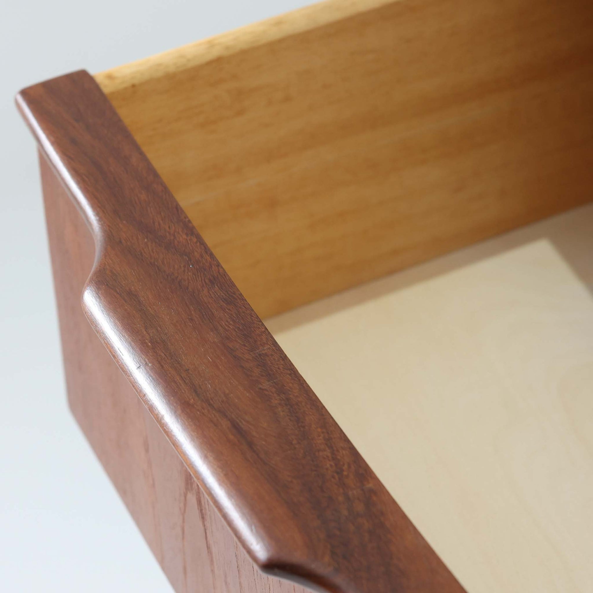 北欧ビンテージらしい端正な佇まいが魅力の5段チェストです。良質な木材を用いた本体は、横に流れる美しい木目に加え、角だけでなく前板を含む本体全体が緩やかな曲線を描く、有機的で上質なフォルムが特徴です。引き出し前板には手掛け一体型の彫り込みが施され、丸みを帯びた造形と相まって柔らかな印象を与えます。高い工作精度が感じられるクオリティの高い一台で、収納力に優れたサイズながら脚付き構造により軽やかさも備え、寝室やリビングの主収納として活躍します。Vordingborg Mobelfabrik社製と伝えられていますが確証はなく、メーカー不詳のビンテージ品としてご紹介します。経年変化によって深みを増した木肌が、空間に上質な存在感をもたらします。