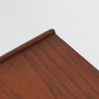 北欧ビンテージらしい端正な佇まいが魅力の5段チェストです。良質な木材を用いた本体は、横に流れる美しい木目に加え、角だけでなく前板を含む本体全体が緩やかな曲線を描く、有機的で上質なフォルムが特徴です。引き出し前板には手掛け一体型の彫り込みが施され、丸みを帯びた造形と相まって柔らかな印象を与えます。高い工作精度が感じられるクオリティの高い一台で、収納力に優れたサイズながら脚付き構造により軽やかさも備え、寝室やリビングの主収納として活躍します。Vordingborg Mobelfabrik社製と伝えられていますが確証はなく、メーカー不詳のビンテージ品としてご紹介します。経年変化によって深みを増した木肌が、空間に上質な存在感をもたらします。