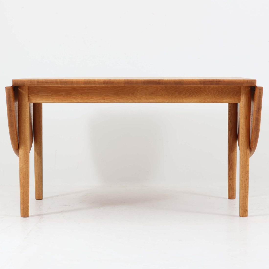 Hans J. Wegnerがデザインし、Getama社より製造されたセンターテーブル「GE82」は、丸脚の意匠が特徴で、四角脚の「GE85」と同時期にデザインされたといわれています。バタフライ構造による拡張機能を備えた北欧ビンテージ家具で、オーク無垢材を贅沢に使用し、幅103cmから160cmへと用途に応じてサイズ調整が可能。普段はコンパクトに、来客時には広々と使える実用性が魅力です。シンプルで力強いフォルムと無垢材ならではの豊かな木目は、年月を経て一層の味わいを増し、空間に温もりと存在感を添えます。