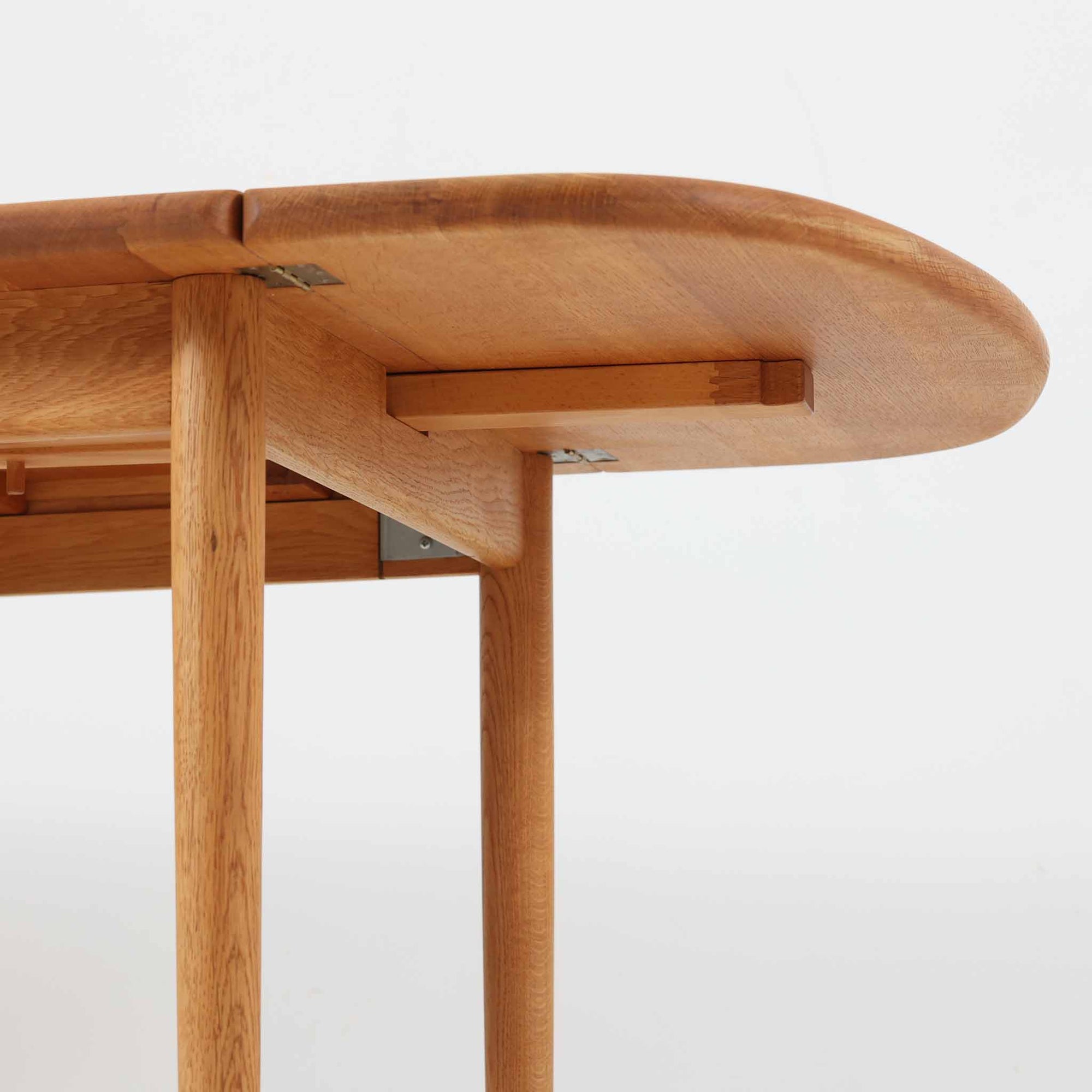 Hans J. Wegnerがデザインし、Getama社より製造されたセンターテーブル「GE82」は、丸脚の意匠が特徴で、四角脚の「GE85」と同時期にデザインされたといわれています。バタフライ構造による拡張機能を備えた北欧ビンテージ家具で、オーク無垢材を贅沢に使用し、幅103cmから160cmへと用途に応じてサイズ調整が可能。普段はコンパクトに、来客時には広々と使える実用性が魅力です。シンプルで力強いフォルムと無垢材ならではの豊かな木目は、年月を経て一層の味わいを増し、空間に温もりと存在感を添えます。