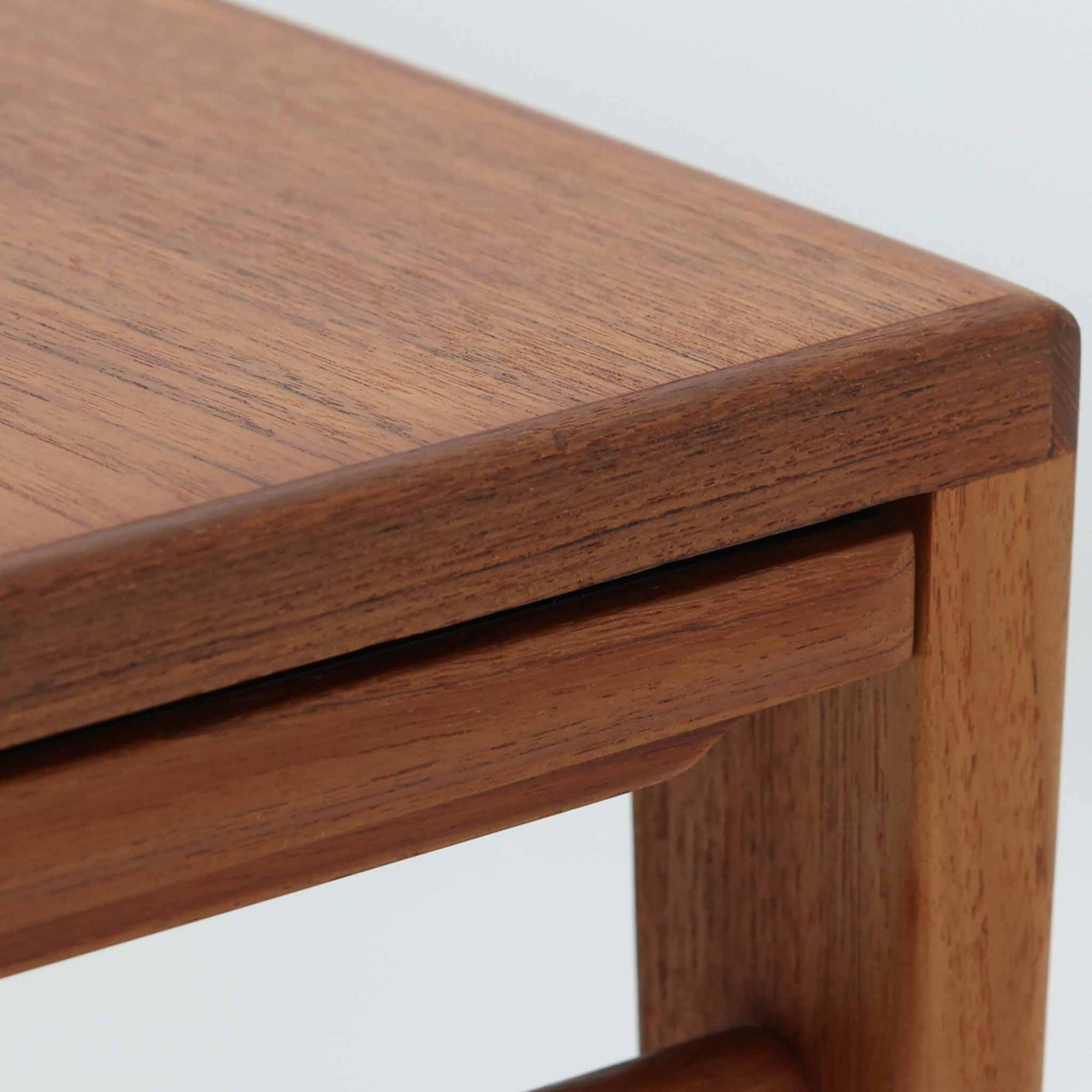 チーク材を用いたデンマーク製の拡張板付きセンターテーブルです。直線的で軽やかなフレーム構造と、脚部から天板へとつながる端正な接合部に北欧ビンテージらしい丁寧なつくりが感じられます。拡張板を引き出すことで天板幅を大きく広げることができ、来客時や作業スペースとしても柔軟に対応します。深みを増したチークの色合いと美しい木目が空間に落ち着きを与え、リビングの主役として長く愛用できる一台です。拡張板はチーク材のほか、黒のラミネート仕上げの2種類が備わっており、用途に応じて使い分けが可能です。ラミネート面は輪染みがつきにくく、作業用や来客時にも気兼ねなく使える実用性を備えています。