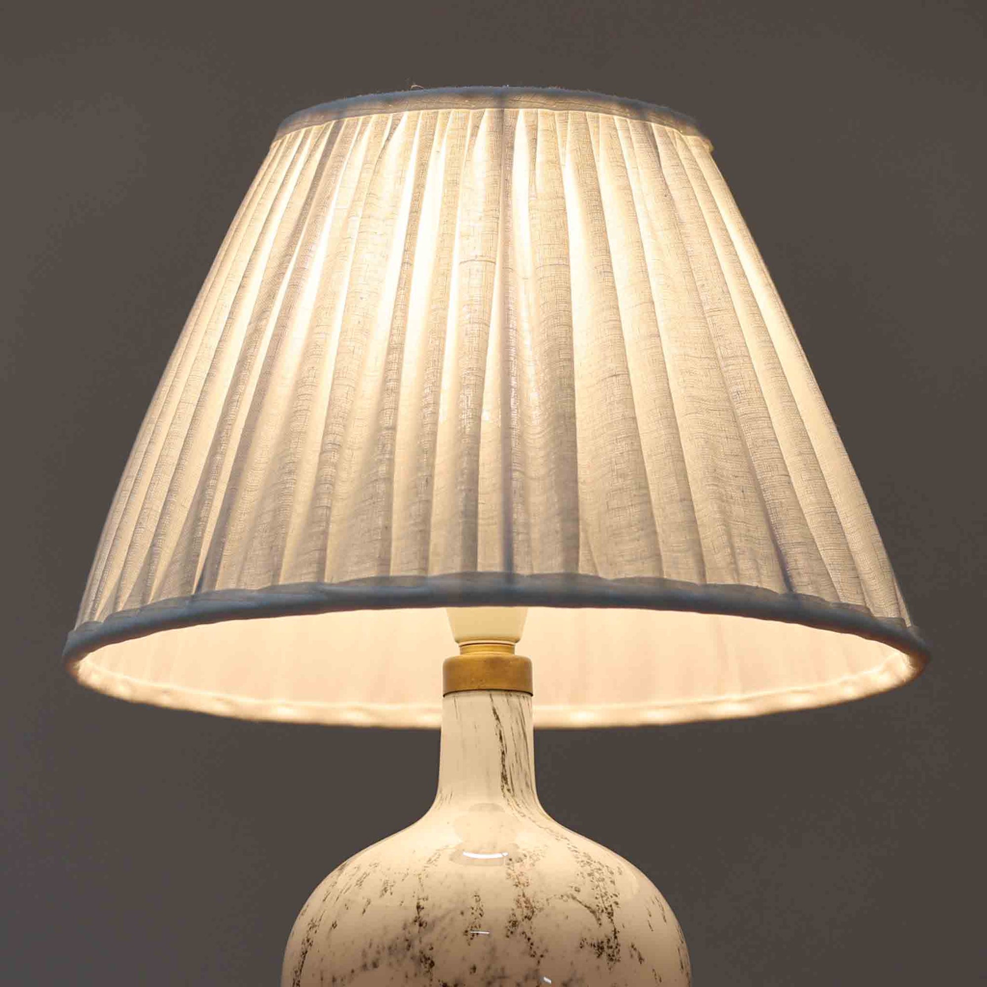 デンマークを代表するガラスメーカー、Holmegaard社よりMichael Bangが手掛けた「LAMP ART」テーブルランプは、高さ40cmのバランス良いサイズ感で、北欧ビンテージの魅力を放ちます。ベースはホワイトガラスにマーブル状の模様が施され、柔らかな光を映し出す造形美が特徴です。真鍮のパーツがアクセントとなり、リネンシェードを透過する光は空間に穏やかな温もりを添えます。洗練されたデザインと職人技が調和した一点物で、リビングや寝室の雰囲気を格上げする逸品です。