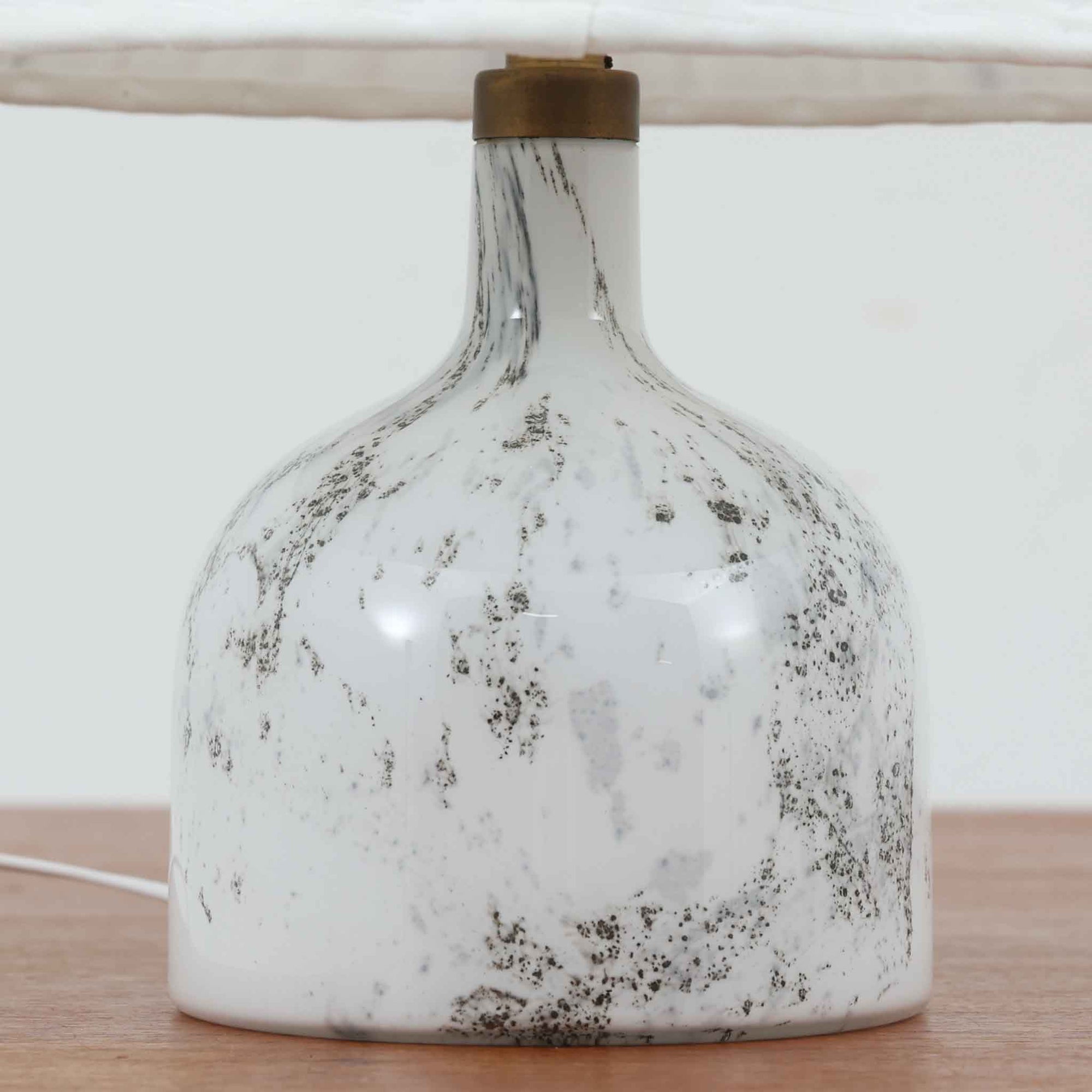 デンマークを代表するガラスメーカー、Holmegaard社よりMichael Bangが手掛けた「LAMP ART」テーブルランプは、高さ40cmのバランス良いサイズ感で、北欧ビンテージの魅力を放ちます。ベースはホワイトガラスにマーブル状の模様が施され、柔らかな光を映し出す造形美が特徴です。真鍮のパーツがアクセントとなり、リネンシェードを透過する光は空間に穏やかな温もりを添えます。洗練されたデザインと職人技が調和した一点物で、リビングや寝室の雰囲気を格上げする逸品です。