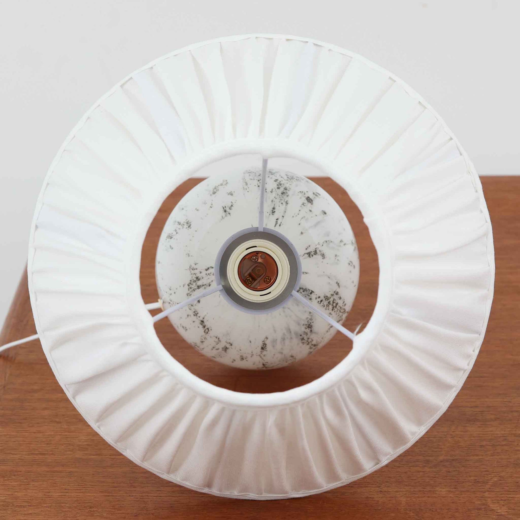 デンマークを代表するガラスメーカー、Holmegaard社よりMichael Bangが手掛けた「LAMP ART」テーブルランプは、高さ40cmのバランス良いサイズ感で、北欧ビンテージの魅力を放ちます。ベースはホワイトガラスにマーブル状の模様が施され、柔らかな光を映し出す造形美が特徴です。真鍮のパーツがアクセントとなり、リネンシェードを透過する光は空間に穏やかな温もりを添えます。洗練されたデザインと職人技が調和した一点物で、リビングや寝室の雰囲気を格上げする逸品です。