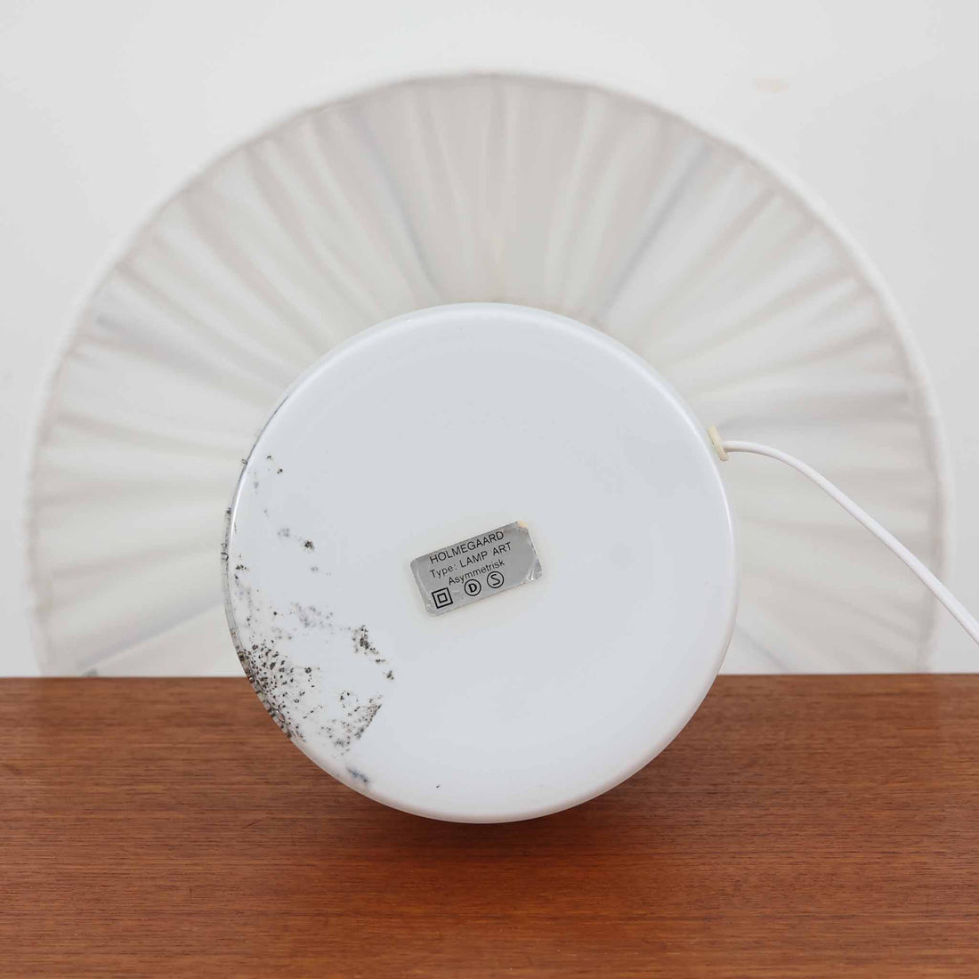 デンマークを代表するガラスメーカー、Holmegaard社よりMichael Bangが手掛けた「LAMP ART」テーブルランプは、高さ40cmのバランス良いサイズ感で、北欧ビンテージの魅力を放ちます。ベースはホワイトガラスにマーブル状の模様が施され、柔らかな光を映し出す造形美が特徴です。真鍮のパーツがアクセントとなり、リネンシェードを透過する光は空間に穏やかな温もりを添えます。洗練されたデザインと職人技が調和した一点物で、リビングや寝室の雰囲気を格上げする逸品です。