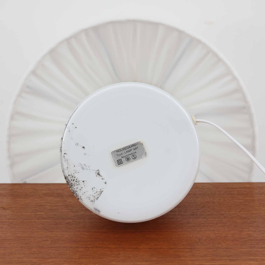 デンマークを代表するガラスメーカー、Holmegaard社よりMichael Bangが手掛けた「LAMP ART」テーブルランプは、高さ40cmのバランス良いサイズ感で、北欧ビンテージの魅力を放ちます。ベースはホワイトガラスにマーブル状の模様が施され、柔らかな光を映し出す造形美が特徴です。真鍮のパーツがアクセントとなり、リネンシェードを透過する光は空間に穏やかな温もりを添えます。洗練されたデザインと職人技が調和した一点物で、リビングや寝室の雰囲気を格上げする逸品です。