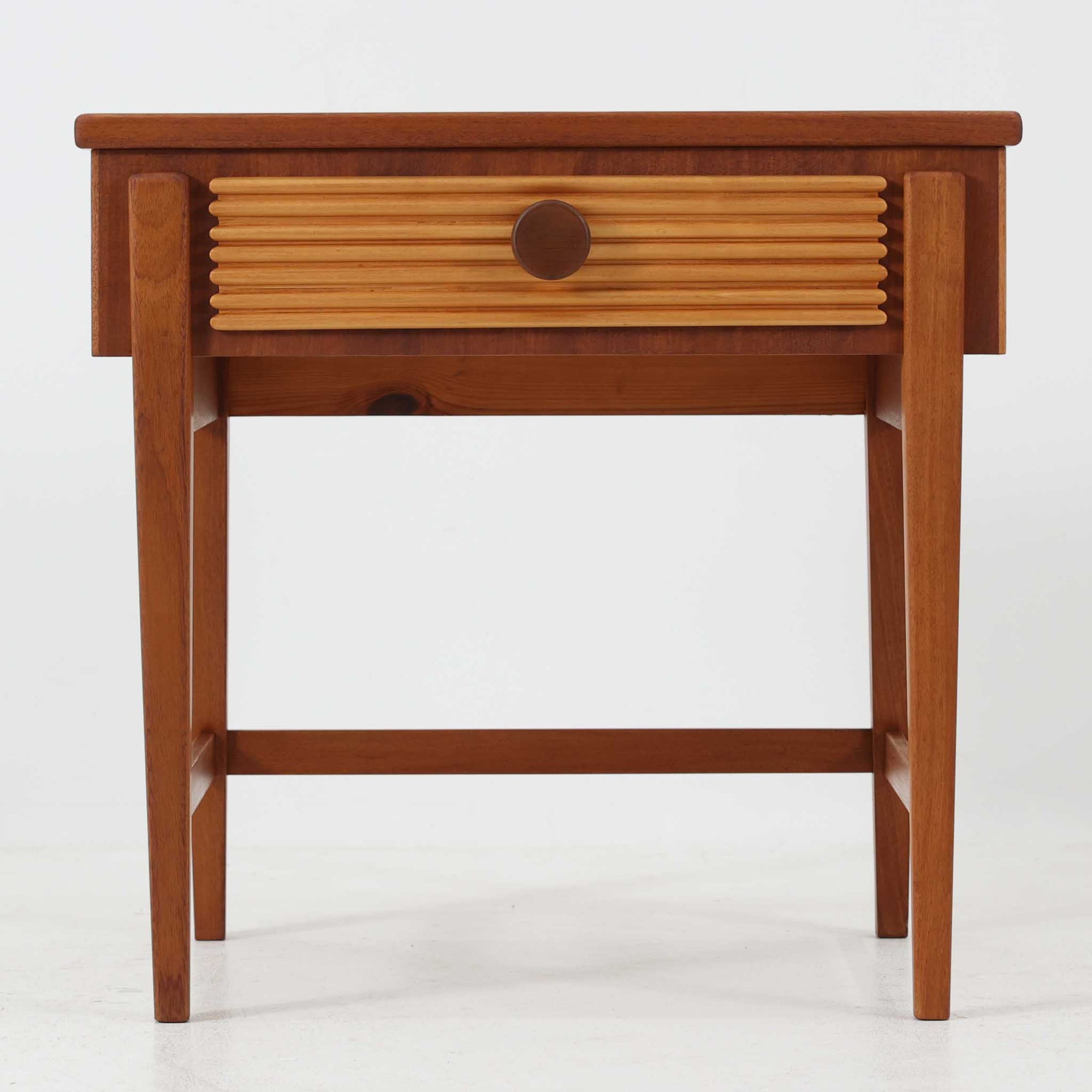 デンマークのサイドチェストです。アフロモシア材の落ち着いた色味の本体に、ビーチ材で成形された横溝装飾の引き出し前板がアクセントとなり、シンプルな構造の中にリズム感のある表情を生み出しています。幅54cmのコンパクトなサイズで、ベッドサイドやソファ脇、玄関先などにも取り入れやすく、引き出し付きで実用性も十分です。経年により深まった木肌の風合いと丁寧なつくりが、北欧ビンテージらしい静かな存在感を空間に添えてくれます。