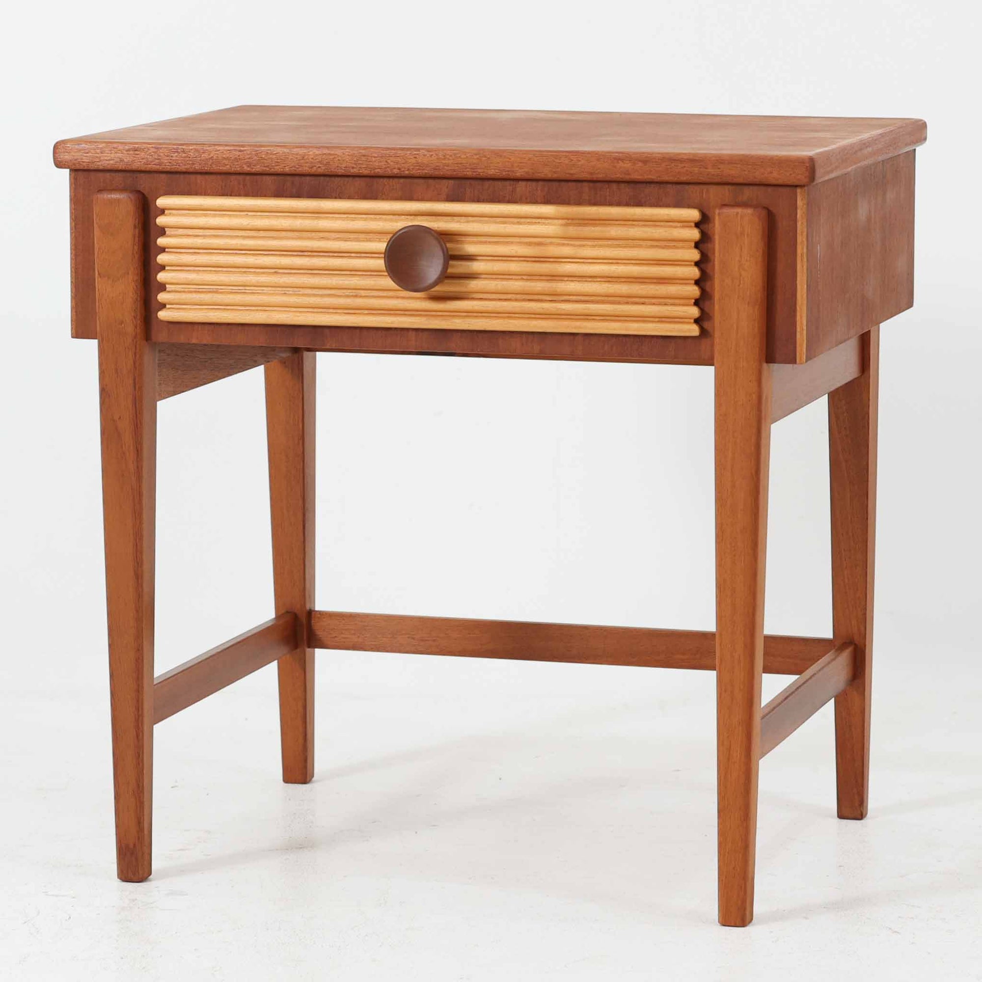 デンマークのサイドチェストです。アフロモシア材の落ち着いた色味の本体に、ビーチ材で成形された横溝装飾の引き出し前板がアクセントとなり、シンプルな構造の中にリズム感のある表情を生み出しています。幅54cmのコンパクトなサイズで、ベッドサイドやソファ脇、玄関先などにも取り入れやすく、引き出し付きで実用性も十分です。経年により深まった木肌の風合いと丁寧なつくりが、北欧ビンテージらしい静かな存在感を空間に添えてくれます。