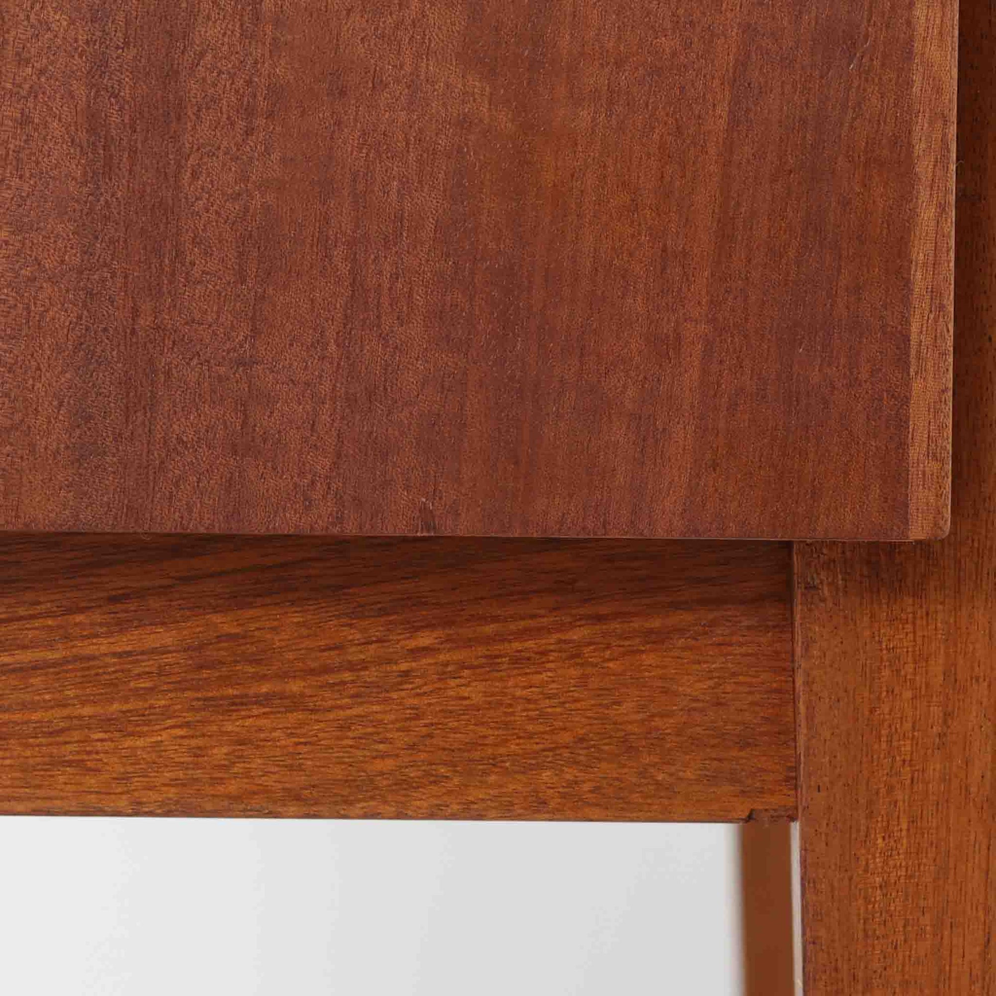 デンマークのサイドチェストです。アフロモシア材の落ち着いた色味の本体に、ビーチ材で成形された横溝装飾の引き出し前板がアクセントとなり、シンプルな構造の中にリズム感のある表情を生み出しています。幅54cmのコンパクトなサイズで、ベッドサイドやソファ脇、玄関先などにも取り入れやすく、引き出し付きで実用性も十分です。経年により深まった木肌の風合いと丁寧なつくりが、北欧ビンテージらしい静かな存在感を空間に添えてくれます。