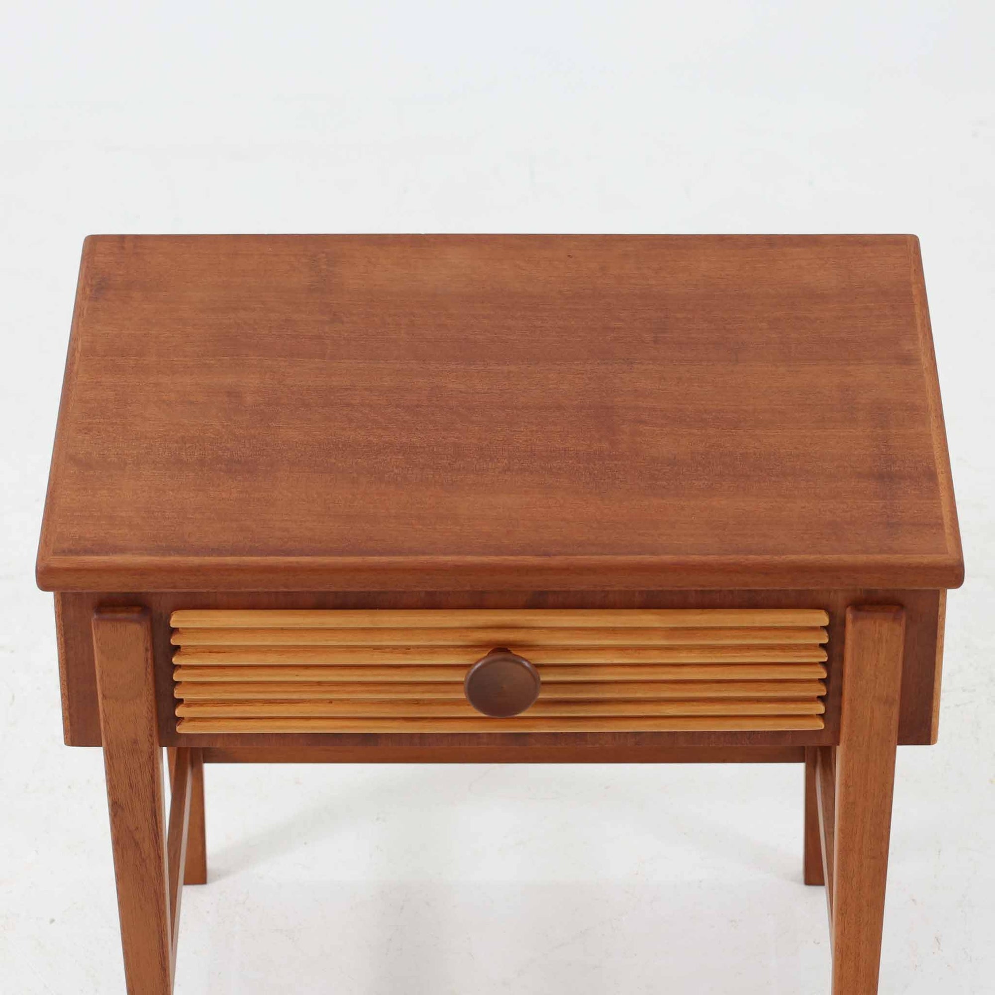 デンマークのサイドチェストです。アフロモシア材の落ち着いた色味の本体に、ビーチ材で成形された横溝装飾の引き出し前板がアクセントとなり、シンプルな構造の中にリズム感のある表情を生み出しています。幅54cmのコンパクトなサイズで、ベッドサイドやソファ脇、玄関先などにも取り入れやすく、引き出し付きで実用性も十分です。経年により深まった木肌の風合いと丁寧なつくりが、北欧ビンテージらしい静かな存在感を空間に添えてくれます。