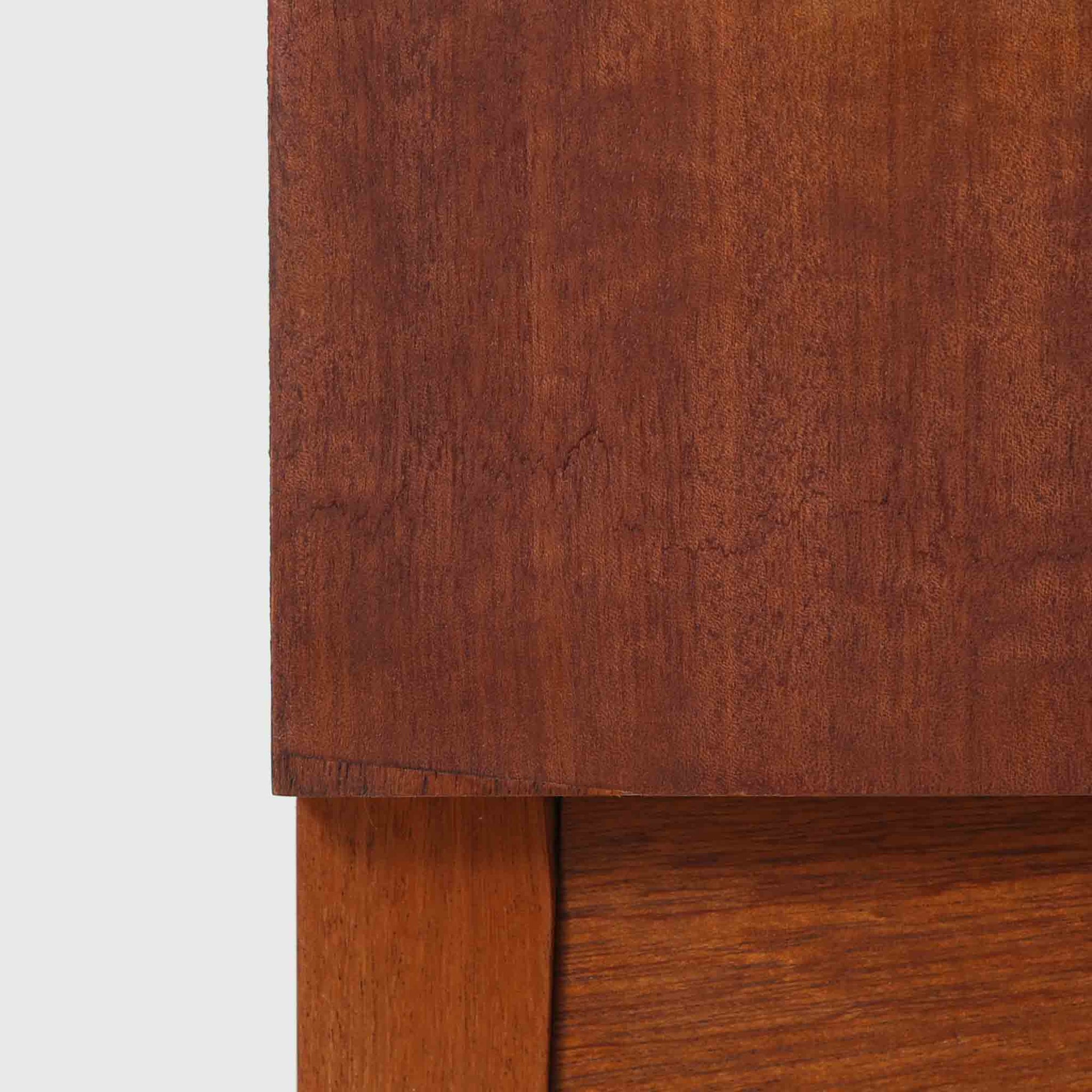 デンマークのサイドチェストです。アフロモシア材の落ち着いた色味の本体に、ビーチ材で成形された横溝装飾の引き出し前板がアクセントとなり、シンプルな構造の中にリズム感のある表情を生み出しています。幅54cmのコンパクトなサイズで、ベッドサイドやソファ脇、玄関先などにも取り入れやすく、引き出し付きで実用性も十分です。経年により深まった木肌の風合いと丁寧なつくりが、北欧ビンテージらしい静かな存在感を空間に添えてくれます。