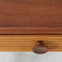 デンマークのサイドチェストです。アフロモシア材の落ち着いた色味の本体に、ビーチ材で成形された横溝装飾の引き出し前板がアクセントとなり、シンプルな構造の中にリズム感のある表情を生み出しています。幅54cmのコンパクトなサイズで、ベッドサイドやソファ脇、玄関先などにも取り入れやすく、引き出し付きで実用性も十分です。経年により深まった木肌の風合いと丁寧なつくりが、北欧ビンテージらしい静かな存在感を空間に添えてくれます。