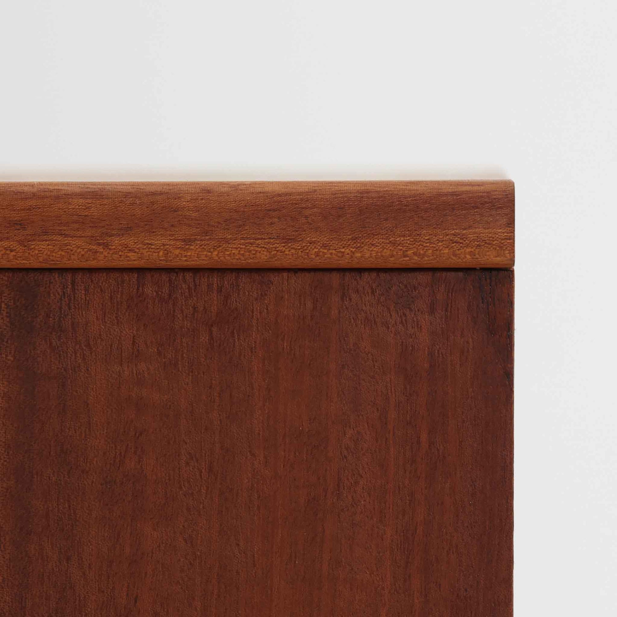 デンマークのサイドチェストです。アフロモシア材の落ち着いた色味の本体に、ビーチ材で成形された横溝装飾の引き出し前板がアクセントとなり、シンプルな構造の中にリズム感のある表情を生み出しています。幅54cmのコンパクトなサイズで、ベッドサイドやソファ脇、玄関先などにも取り入れやすく、引き出し付きで実用性も十分です。経年により深まった木肌の風合いと丁寧なつくりが、北欧ビンテージらしい静かな存在感を空間に添えてくれます。