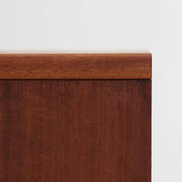 デンマークのサイドチェストです。アフロモシア材の落ち着いた色味の本体に、ビーチ材で成形された横溝装飾の引き出し前板がアクセントとなり、シンプルな構造の中にリズム感のある表情を生み出しています。幅54cmのコンパクトなサイズで、ベッドサイドやソファ脇、玄関先などにも取り入れやすく、引き出し付きで実用性も十分です。経年により深まった木肌の風合いと丁寧なつくりが、北欧ビンテージらしい静かな存在感を空間に添えてくれます。