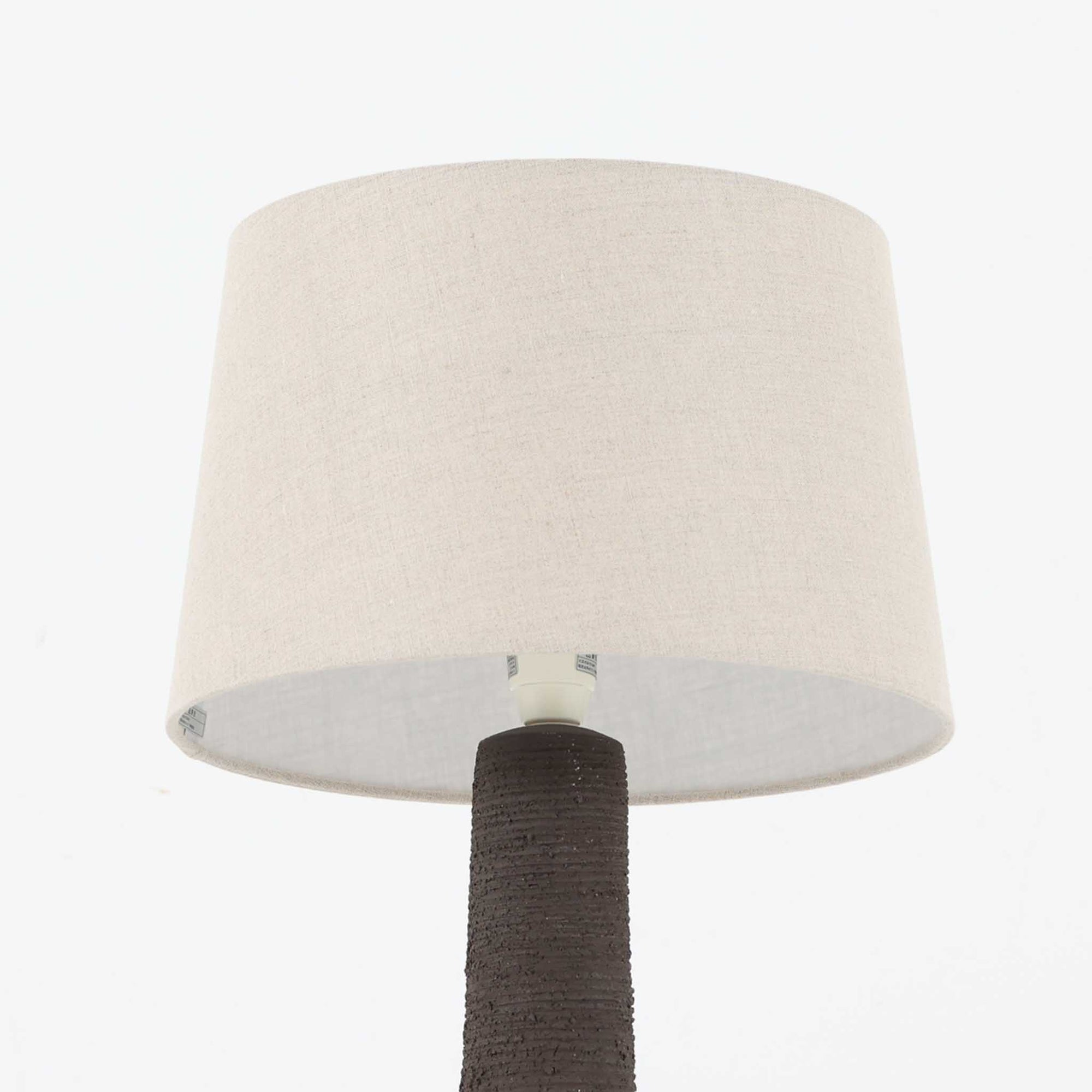 Soholm Keramik（スーホルム・セラミック）製による高さ95cmのビンテージランプです。ベースには緑色の釉薬で仕上げられた陶磁器が用いられ、花模様のレリーフが浮かび上がる温かみのあるデザインが魅力です。細身で長く伸びた支柱部分には素朴な質感が活かされ、上部にはシンプルなリネンシェードを合わせることで、柔らかな光を優しく拡散します。陶器製ランプとしては稀に見る大きさで、テーブルランプでありながらフロアランプのような存在感を放ち、リビングのアクセントや間接照明としても活躍します。陶芸的な味わいと経年の風合いが調和した、北欧ビンテージならではの逸品です。