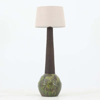 Soholm Keramik（スーホルム・セラミック）製による高さ95cmのビンテージランプです。ベースには緑色の釉薬で仕上げられた陶磁器が用いられ、花模様のレリーフが浮かび上がる温かみのあるデザインが魅力です。細身で長く伸びた支柱部分には素朴な質感が活かされ、上部にはシンプルなリネンシェードを合わせることで、柔らかな光を優しく拡散します。陶器製ランプとしては稀に見る大きさで、テーブルランプでありながらフロアランプのような存在感を放ち、リビングのアクセントや間接照明としても活躍します。陶芸的な味わいと経年の風合いが調和した、北欧ビンテージならではの逸品です。