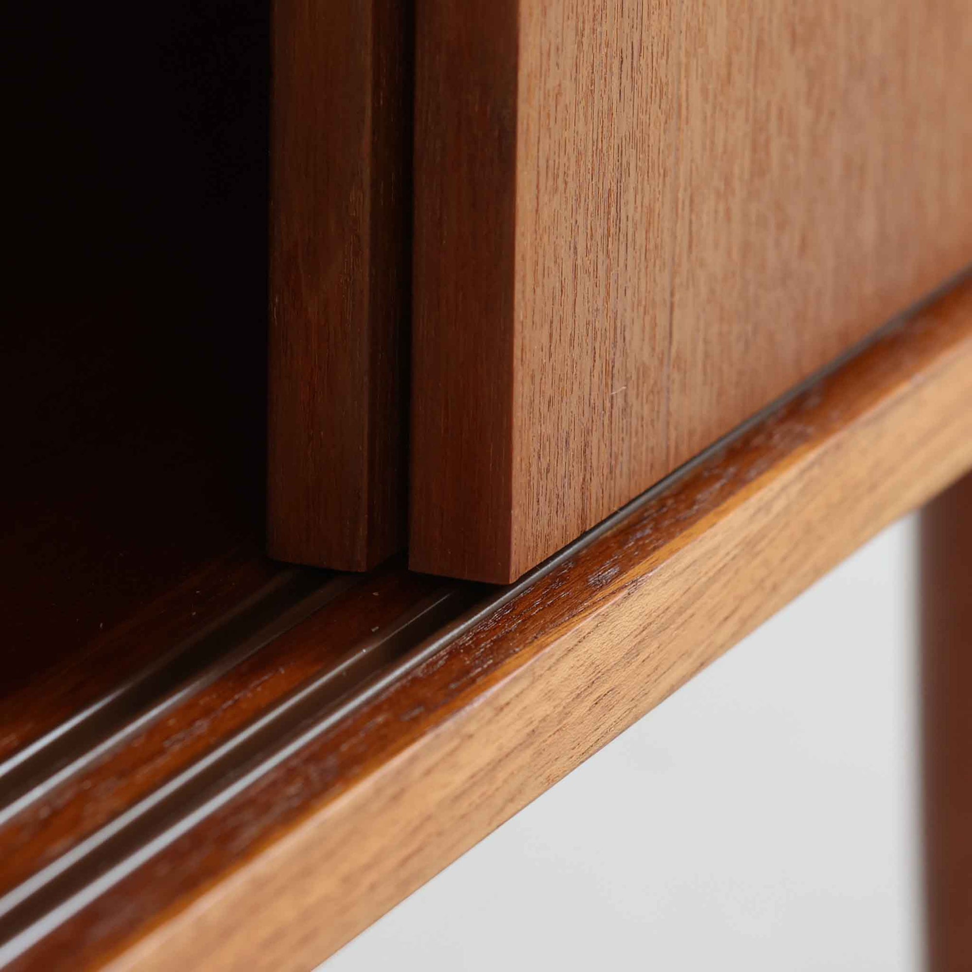 こちらの小ぶりなボードは、温かみのあるチーク材を用いたすっきりとした佇まいが魅力の北欧ビンテージ家具で、スライド扉を開くと左右に棚板付きの収納スペースが現れ、日用品や小物を効率よく整理できます。直線的な箱型の構造に、細身でテーパーの効いた脚部が軽やかな印象を添え、コンパクトながら存在感のある設計が空間に落ち着いたアクセントをもたらします。経年で深まった木肌の質感も味わい深く、リビングや玄関脇のサイド収納としても取り入れやすい一台です。