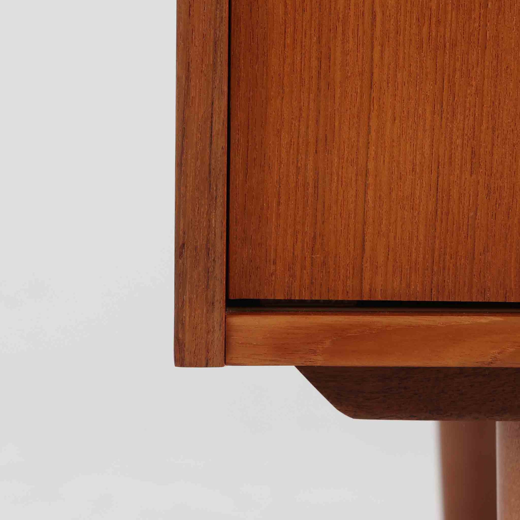 こちらの小ぶりなボードは、温かみのあるチーク材を用いたすっきりとした佇まいが魅力の北欧ビンテージ家具で、スライド扉を開くと左右に棚板付きの収納スペースが現れ、日用品や小物を効率よく整理できます。直線的な箱型の構造に、細身でテーパーの効いた脚部が軽やかな印象を添え、コンパクトながら存在感のある設計が空間に落ち着いたアクセントをもたらします。経年で深まった木肌の質感も味わい深く、リビングや玄関脇のサイド収納としても取り入れやすい一台です。