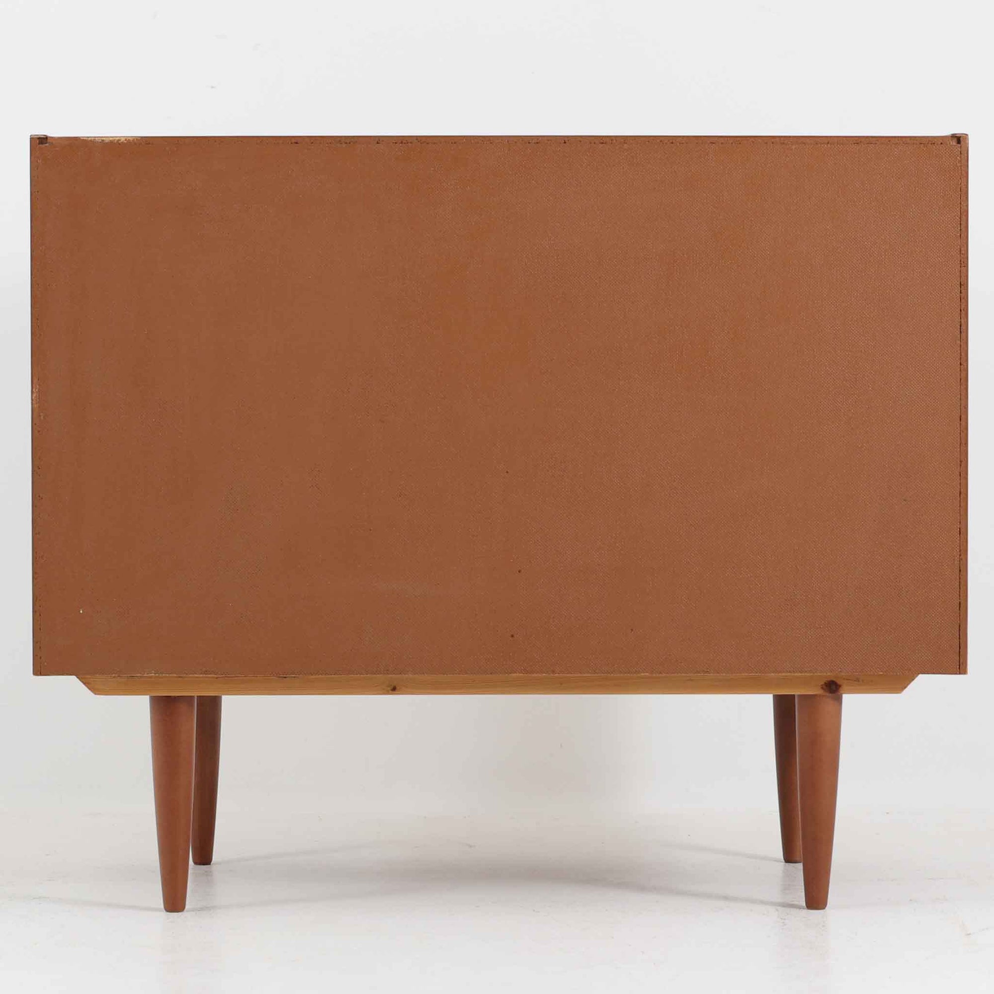 こちらの小ぶりなボードは、温かみのあるチーク材を用いたすっきりとした佇まいが魅力の北欧ビンテージ家具で、スライド扉を開くと左右に棚板付きの収納スペースが現れ、日用品や小物を効率よく整理できます。直線的な箱型の構造に、細身でテーパーの効いた脚部が軽やかな印象を添え、コンパクトながら存在感のある設計が空間に落ち着いたアクセントをもたらします。経年で深まった木肌の質感も味わい深く、リビングや玄関脇のサイド収納としても取り入れやすい一台です。