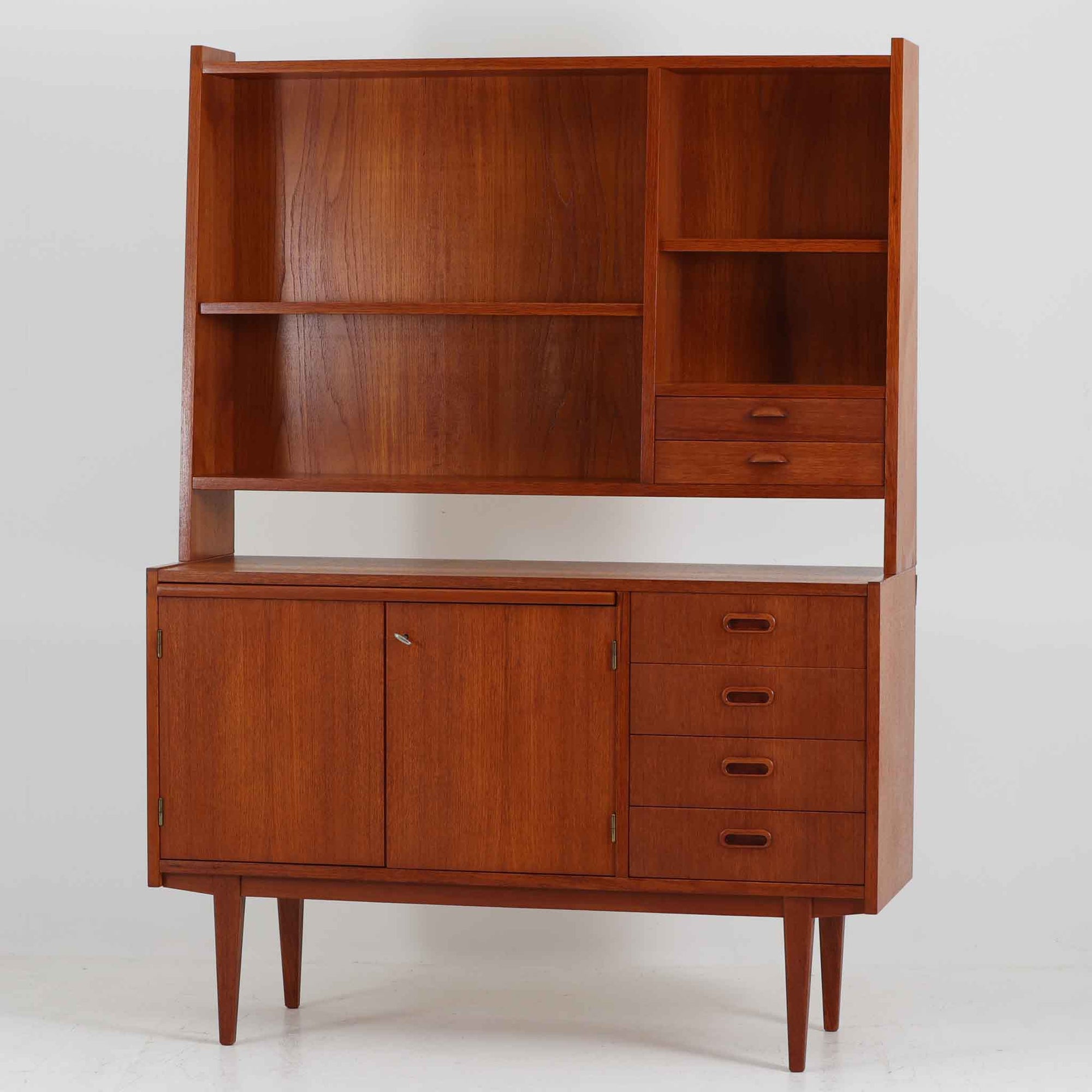 スウェーデン製のディスプレイシェルフです。チーク材の温かみある木目が美しく、上段にはオープンシェルフと小引き出し、下段には引き棚と引き戸収納と4段の引き出しが備わった実用性の高いデザインです。下段収納部には奥行きの浅い棚板が設けられており、収納する物に応じて使い分けができます。食器や本、雑貨などをすっきりと整理しながら、見せる収納としても楽しめます。扉の錠前は故障しているため施錠・開錠はできませんが、本鍵を取手として使用できるようにしています。また、扉をしっかり固定するためローラーキャッチを新たに取り付け済みです。引き出しはスムーズに開閉でき、細部まで丁寧に仕上げられています。細身のテーパー脚が全体を軽やかに見せ、経年で深みを増したチークの風合いが空間に上質な落ち着きをもたらす、北欧らしい一台です。
