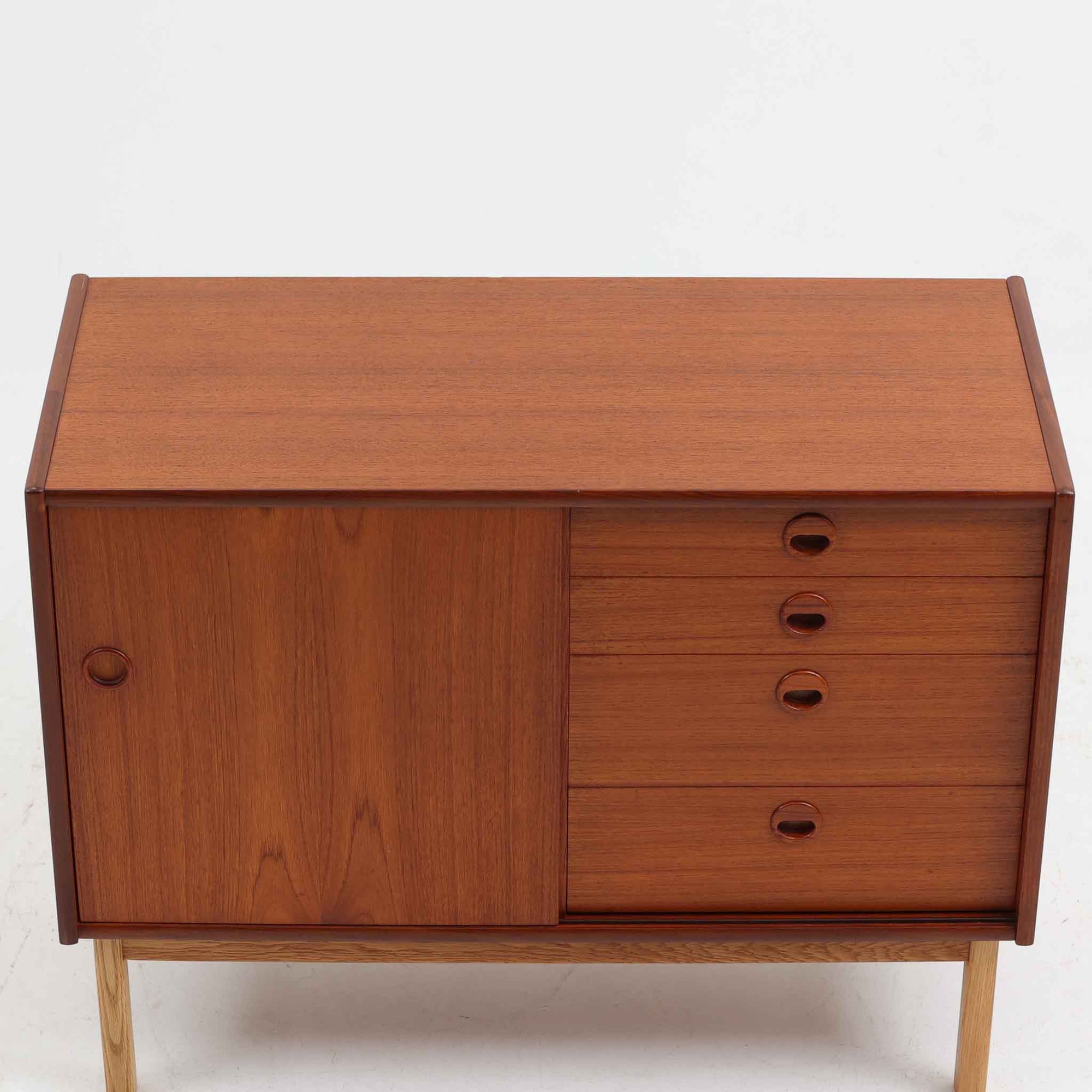 チーク材とオーク材を組み合わせて作られたスウェーデン製のディスプレイシェルフです。幅90cmと使いやすいサイズ感で、上部の棚には本やオブジェを、下部の引き戸と引き出しには日用品を収納できる実用性の高い構成となっています。滑らかな木肌や丁寧な造りには職人技が感じられ、経年により深みを増した木の風合いが空間に温かみをもたらします。リビングやダイニングはもちろん、書斎や寝室の収納兼ディスプレイとしても活躍する、北欧ビンテージ家具らしいシンプルかつ機能的な一台です。