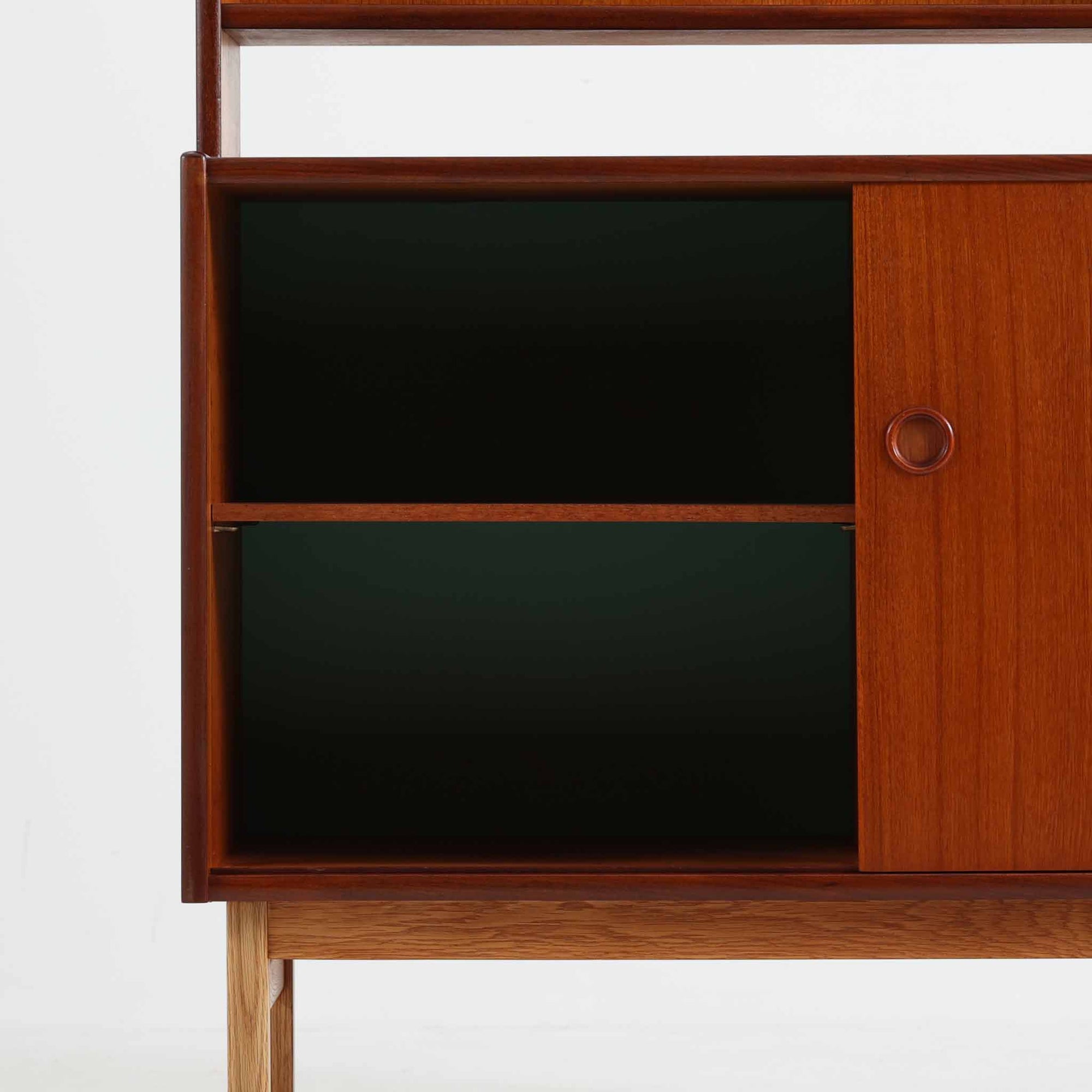 チーク材とオーク材を組み合わせて作られたスウェーデン製のディスプレイシェルフです。幅90cmと使いやすいサイズ感で、上部の棚には本やオブジェを、下部の引き戸と引き出しには日用品を収納できる実用性の高い構成となっています。滑らかな木肌や丁寧な造りには職人技が感じられ、経年により深みを増した木の風合いが空間に温かみをもたらします。リビングやダイニングはもちろん、書斎や寝室の収納兼ディスプレイとしても活躍する、北欧ビンテージ家具らしいシンプルかつ機能的な一台です。