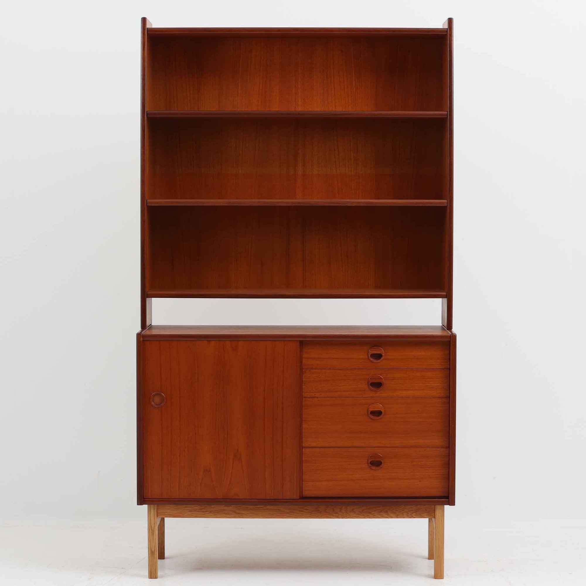 チーク材とオーク材を組み合わせて作られたスウェーデン製のディスプレイシェルフです。幅90cmと使いやすいサイズ感で、上部の棚には本やオブジェを、下部の引き戸と引き出しには日用品を収納できる実用性の高い構成となっています。滑らかな木肌や丁寧な造りには職人技が感じられ、経年により深みを増した木の風合いが空間に温かみをもたらします。リビングやダイニングはもちろん、書斎や寝室の収納兼ディスプレイとしても活躍する、北欧ビンテージ家具らしいシンプルかつ機能的な一台です。