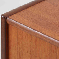 スウェーデン製のチーク材とオーク材を組み合わせたディスプレイシェルフです。幅90cmと程よいサイズ感で、上部の棚は書籍やオブジェの展示に適し、下部の引き戸収納は日用品や小物をすっきりと収めることができます。丸みを帯びた取っ手が温かみのあるアクセントとなり、北欧家具らしいシンプルで実用的なデザインを際立たせています。経年によって深みを増したチークの木目とオークのコントラストが上品な存在感を放ち、リビングや書斎の空間に落ち着いた雰囲気を添えるビンテージ家具です。