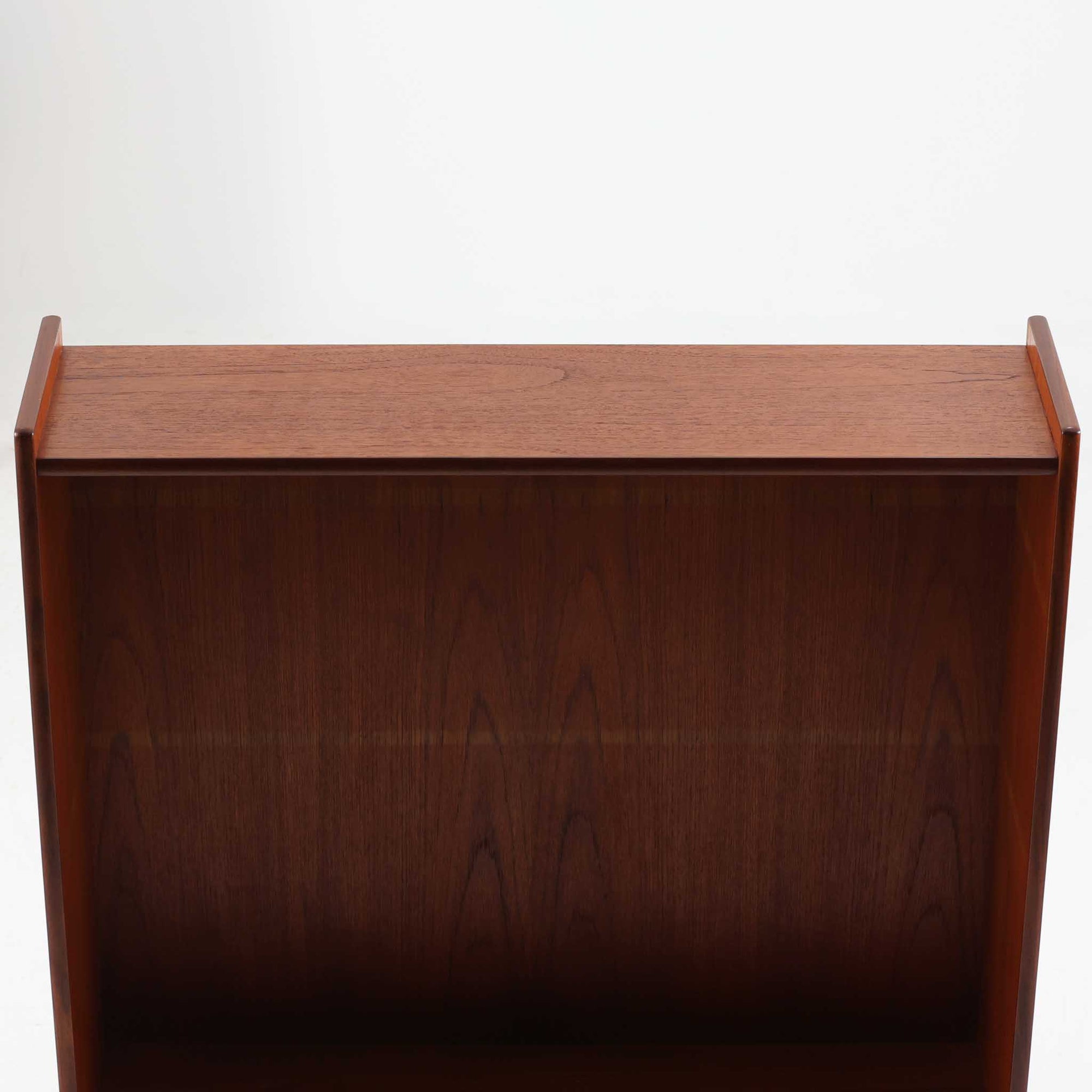 スウェーデン製のチーク材とオーク材を組み合わせたディスプレイシェルフです。幅90cmと程よいサイズ感で、上部の棚は書籍やオブジェの展示に適し、下部の引き戸収納は日用品や小物をすっきりと収めることができます。丸みを帯びた取っ手が温かみのあるアクセントとなり、北欧家具らしいシンプルで実用的なデザインを際立たせています。経年によって深みを増したチークの木目とオークのコントラストが上品な存在感を放ち、リビングや書斎の空間に落ち着いた雰囲気を添えるビンテージ家具です。