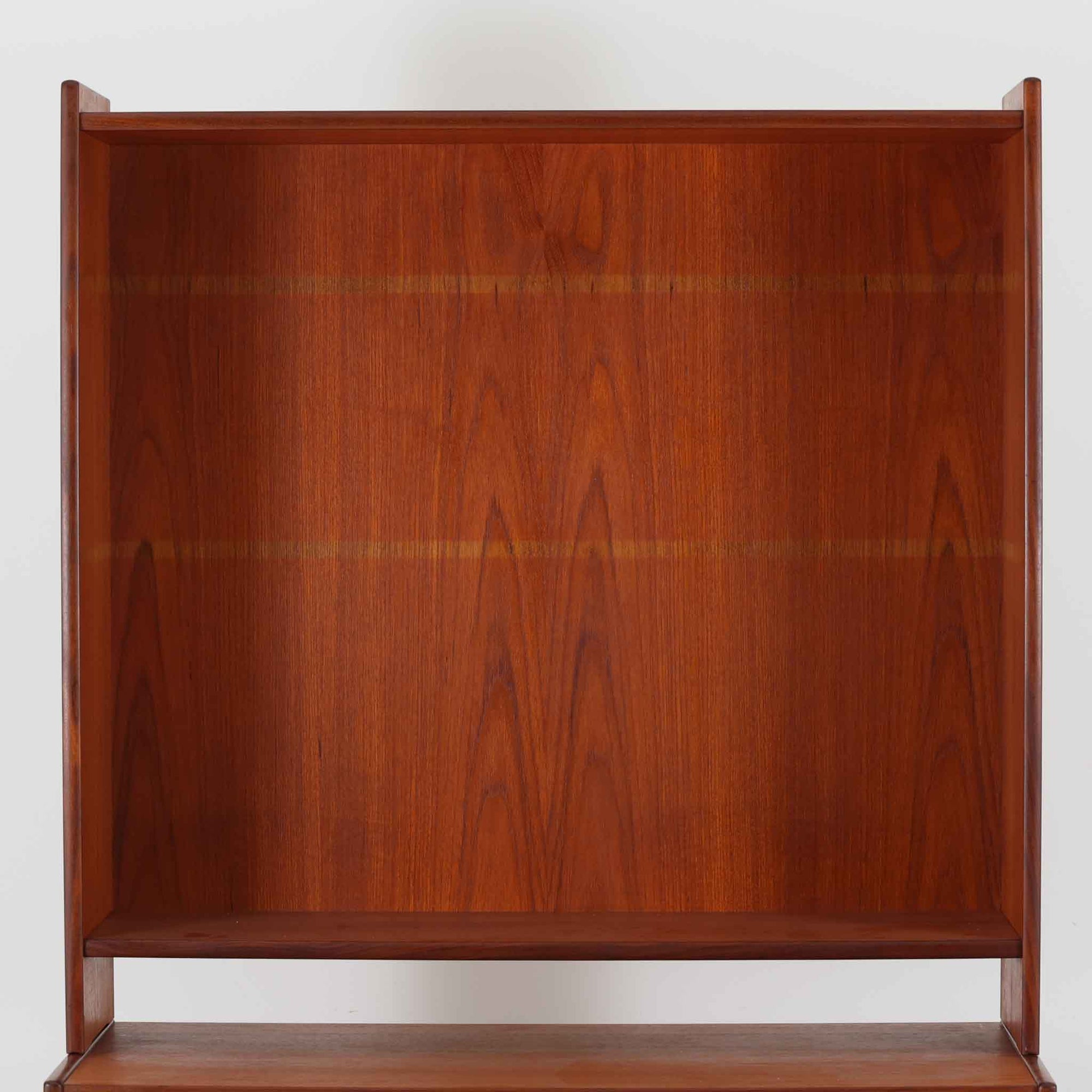 スウェーデン製のチーク材とオーク材を組み合わせたディスプレイシェルフです。幅90cmと程よいサイズ感で、上部の棚は書籍やオブジェの展示に適し、下部の引き戸収納は日用品や小物をすっきりと収めることができます。丸みを帯びた取っ手が温かみのあるアクセントとなり、北欧家具らしいシンプルで実用的なデザインを際立たせています。経年によって深みを増したチークの木目とオークのコントラストが上品な存在感を放ち、リビングや書斎の空間に落ち着いた雰囲気を添えるビンテージ家具です。