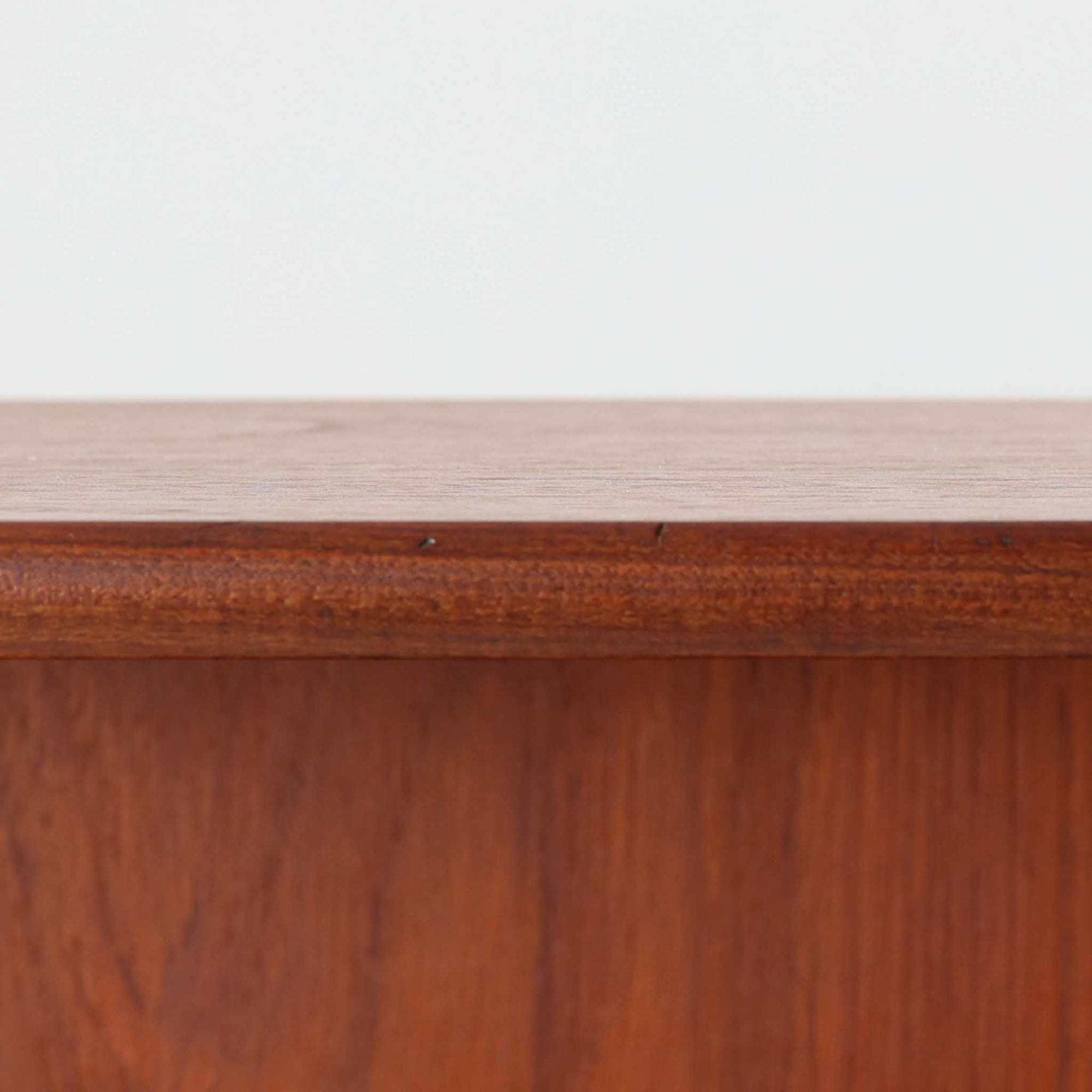 スウェーデン製のチーク材とオーク材を組み合わせたディスプレイシェルフです。幅90cmと程よいサイズ感で、上部の棚は書籍やオブジェの展示に適し、下部の引き戸収納は日用品や小物をすっきりと収めることができます。丸みを帯びた取っ手が温かみのあるアクセントとなり、北欧家具らしいシンプルで実用的なデザインを際立たせています。経年によって深みを増したチークの木目とオークのコントラストが上品な存在感を放ち、リビングや書斎の空間に落ち着いた雰囲気を添えるビンテージ家具です。