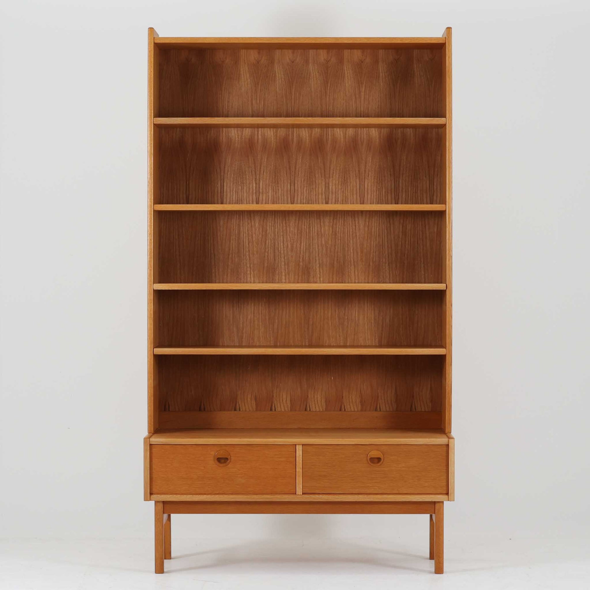 スウェーデン製ディスプレイシェルフです。オーク材の美しい木目と経年により深みを増した色合いが魅力で、背板まで丁寧に木目が通った上質な仕上がりが印象的です。上部は複数の棚板を備え、書籍や雑貨、器などをバランス良く飾れる構造で、下部には引き出しを配し実用性も兼ね備えています。丸みを帯びた取手や細身の脚部が軽やかな印象を与え、北欧らしい洗練された佇まいが空間を上品に演出する一台です。