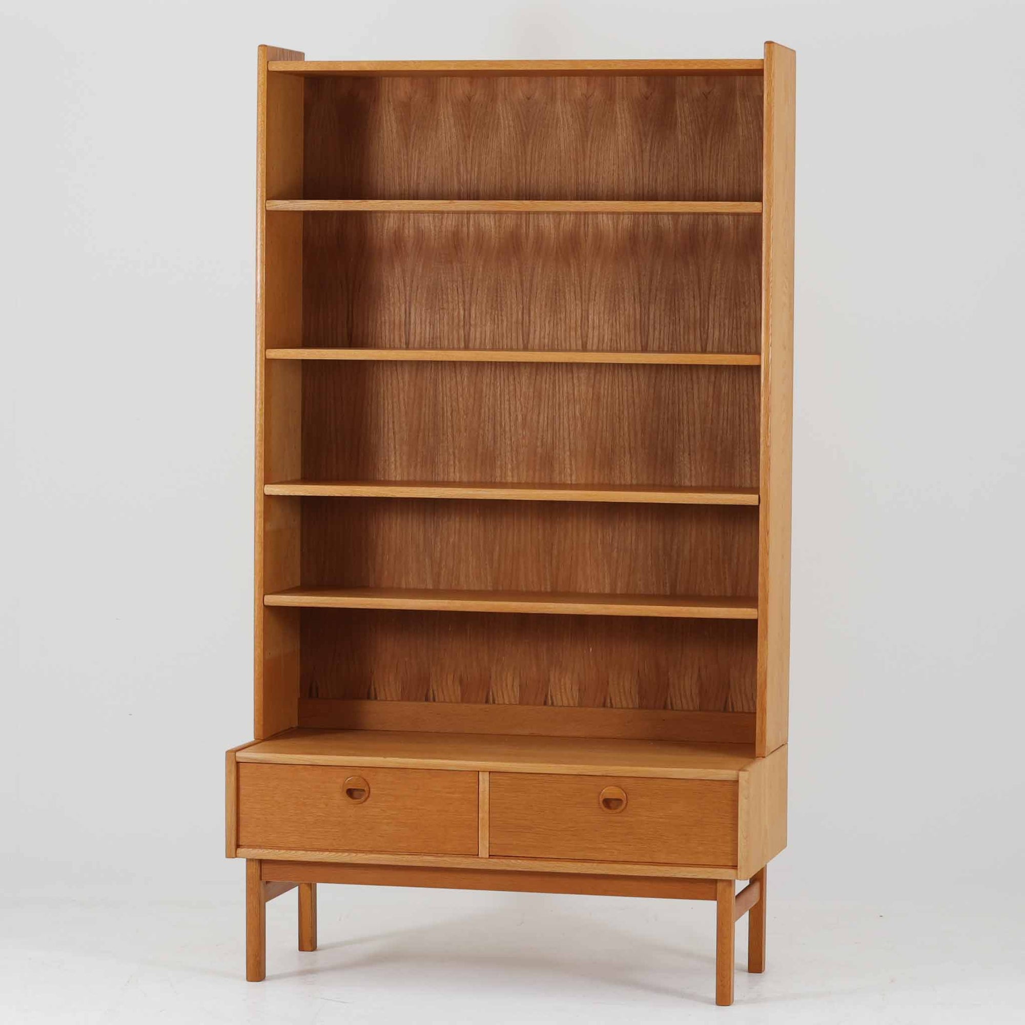 スウェーデン製ディスプレイシェルフです。オーク材の美しい木目と経年により深みを増した色合いが魅力で、背板まで丁寧に木目が通った上質な仕上がりが印象的です。上部は複数の棚板を備え、書籍や雑貨、器などをバランス良く飾れる構造で、下部には引き出しを配し実用性も兼ね備えています。丸みを帯びた取手や細身の脚部が軽やかな印象を与え、北欧らしい洗練された佇まいが空間を上品に演出する一台です。