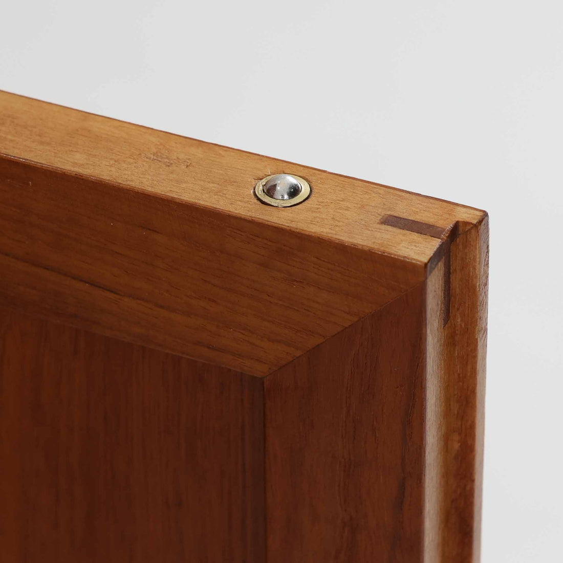 スウェーデン製のディスプレイシェルフです。上部は高さ調整可能な棚板が設けられており、書籍やオブジェの収納・展示に最適です。中央には小引き出しが2杯備わり、カトラリーや小物の整理にも便利。下部には扉付きの収納スペースがあり、日用品をすっきりと収納できます。素材にはチーク（本体）・オーク（脚の幕板）・ビーチ（脚）の3種の木材が用いられ、異なる木目のコントラストが美しい仕上がりです。北欧家具らしい温もりと実用性を兼ね備えた一台で、リビングやダイニング、書斎など幅広いシーンに調和します。