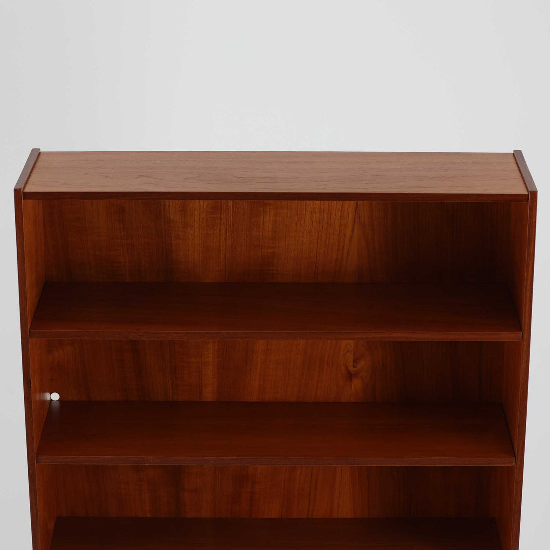 スウェーデン製のディスプレイシェルフです。上部は高さ調整可能な棚板が設けられており、書籍やオブジェの収納・展示に最適です。中央には小引き出しが2杯備わり、カトラリーや小物の整理にも便利。下部には扉付きの収納スペースがあり、日用品をすっきりと収納できます。素材にはチーク（本体）・オーク（脚の幕板）・ビーチ（脚）の3種の木材が用いられ、異なる木目のコントラストが美しい仕上がりです。北欧家具らしい温もりと実用性を兼ね備えた一台で、リビングやダイニング、書斎など幅広いシーンに調和します。