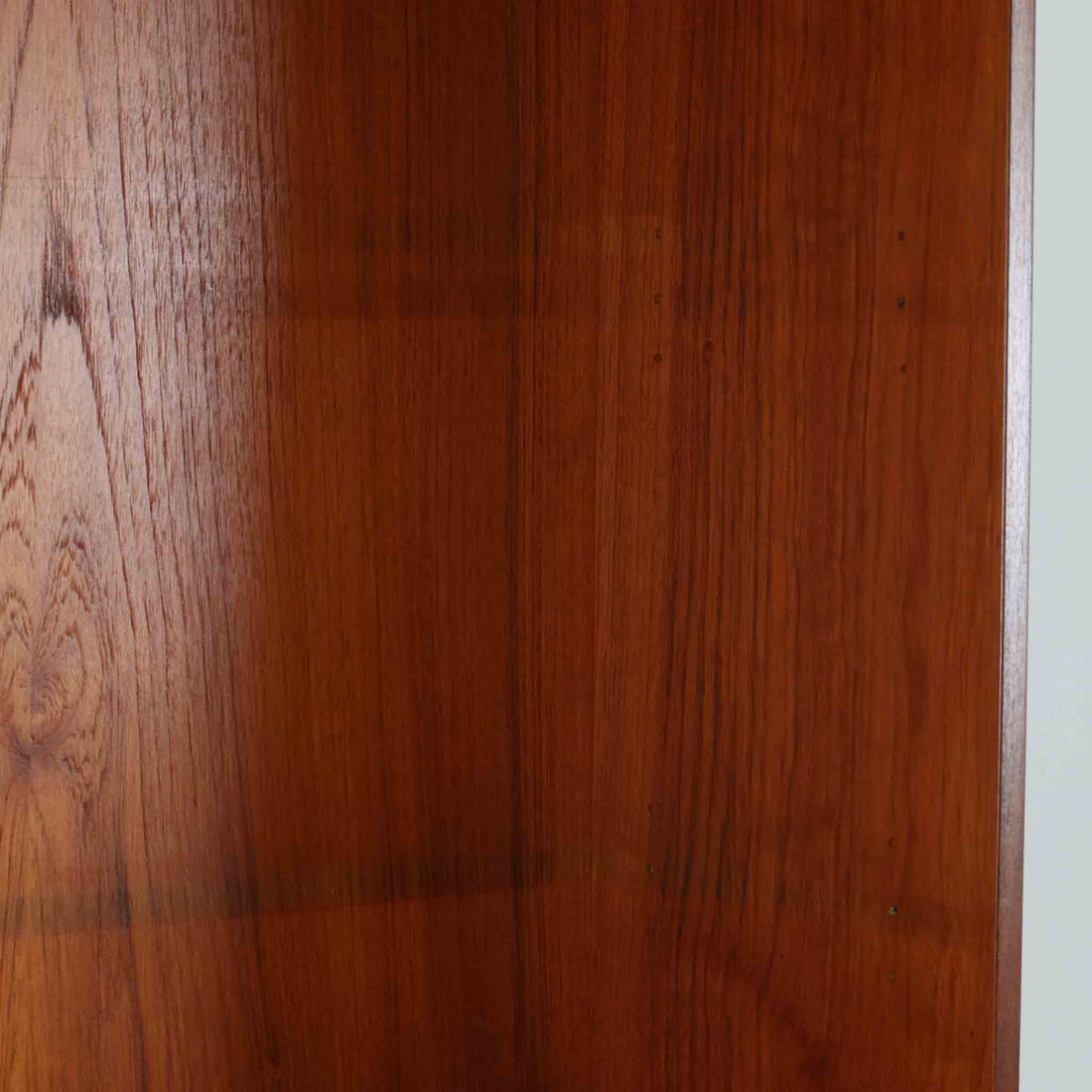 スウェーデン製のディスプレイシェルフです。上部は高さ調整可能な棚板が設けられており、書籍やオブジェの収納・展示に最適です。中央には小引き出しが2杯備わり、カトラリーや小物の整理にも便利。下部には扉付きの収納スペースがあり、日用品をすっきりと収納できます。素材にはチーク（本体）・オーク（脚の幕板）・ビーチ（脚）の3種の木材が用いられ、異なる木目のコントラストが美しい仕上がりです。北欧家具らしい温もりと実用性を兼ね備えた一台で、リビングやダイニング、書斎など幅広いシーンに調和します。