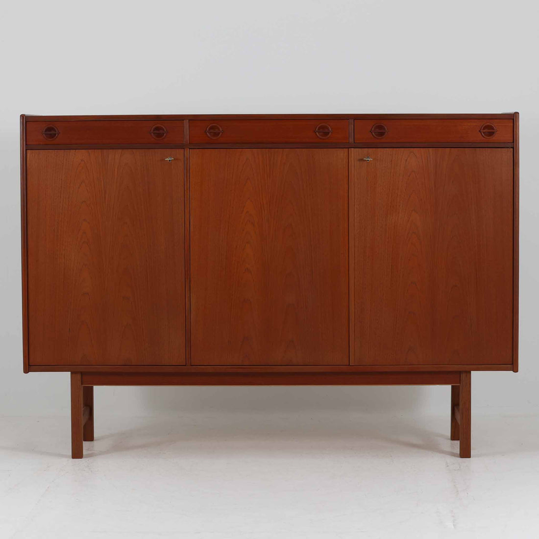 Tage Olofsson（ターゲ・オロフソン）によるデザインで、Ulferts Mobler社製のキッチンキャビネットです。チーク材を贅沢に使用した美しい木目と、丸型の引き手がアクセントとなったデザインが特徴です。上部にはカトラリーなどを整理できる仕切り付きの引き出しが3杯、下部には棚板付きの扉収納が備えられており、食器やキッチン用品を効率的に収納できます。北欧家具らしい温もりと機能性を兼ね備えた一台で、リビングやダイニングにも自然に溶け込む上品な佇まいです。