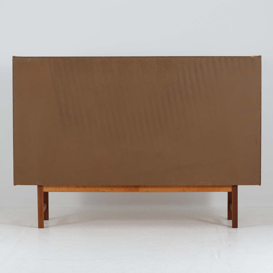 Tage Olofsson（ターゲ・オロフソン）によるデザインで、Ulferts Mobler社製のキッチンキャビネットです。チーク材を贅沢に使用した美しい木目と、丸型の引き手がアクセントとなったデザインが特徴です。上部にはカトラリーなどを整理できる仕切り付きの引き出しが3杯、下部には棚板付きの扉収納が備えられており、食器やキッチン用品を効率的に収納できます。北欧家具らしい温もりと機能性を兼ね備えた一台で、リビングやダイニングにも自然に溶け込む上品な佇まいです。