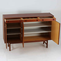 Tage Olofsson（ターゲ・オロフソン）によるデザインで、Ulferts Mobler社製のキッチンキャビネットです。チーク材を贅沢に使用した美しい木目と、丸型の引き手がアクセントとなったデザインが特徴です。上部にはカトラリーなどを整理できる仕切り付きの引き出しが3杯、下部には棚板付きの扉収納が備えられており、食器やキッチン用品を効率的に収納できます。北欧家具らしい温もりと機能性を兼ね備えた一台で、リビングやダイニングにも自然に溶け込む上品な佇まいです。