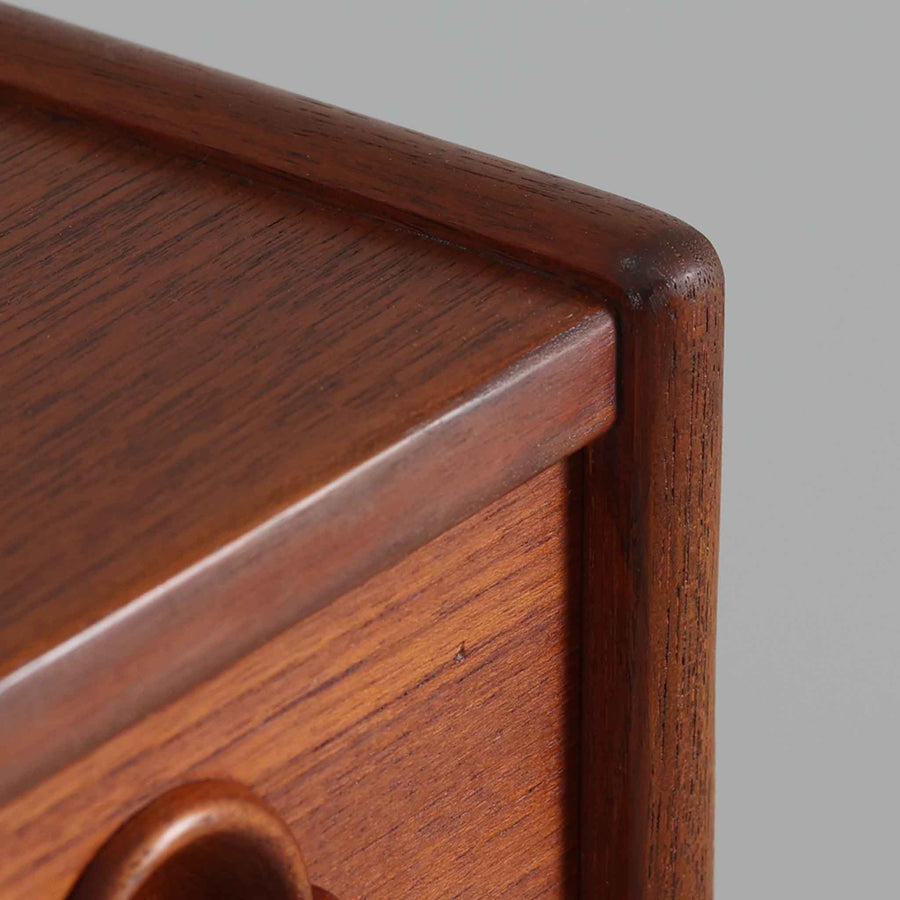 Tage Olofsson（ターゲ・オロフソン）によるデザインで、Ulferts Mobler社製のキッチンキャビネットです。チーク材を贅沢に使用した美しい木目と、丸型の引き手がアクセントとなったデザインが特徴です。上部にはカトラリーなどを整理できる仕切り付きの引き出しが3杯、下部には棚板付きの扉収納が備えられており、食器やキッチン用品を効率的に収納できます。北欧家具らしい温もりと機能性を兼ね備えた一台で、リビングやダイニングにも自然に溶け込む上品な佇まいです。