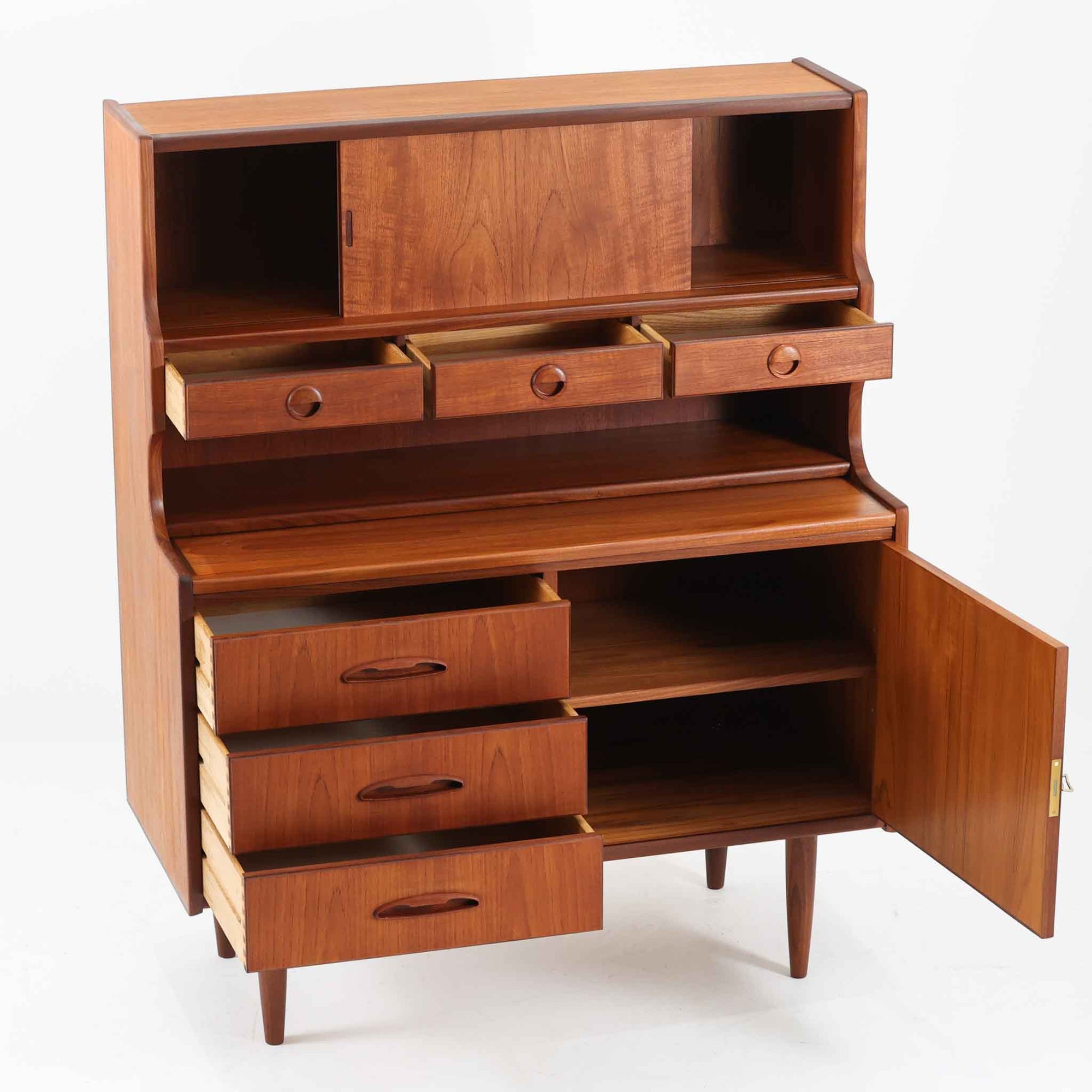 デンマーク製のビンテージライティングビューロです。チーク材を使用した温かみのある木肌と美しい木目が印象的で、北欧家具ならではの上質な存在感を放ちます。上部の引き戸収納や小引き出し、下部の引き出しとキャビネットを備え、機能的に整理できる実用的な設計が魅力。天板をデスクとして使えるため、書き物や作業スペースとしても活躍します。丸みを帯びたフォルムや細身の脚部が軽やかな印象を与え、経年により深みを増したチークの風合いがビンテージ家具ならではの味わいを楽しめる一台です。