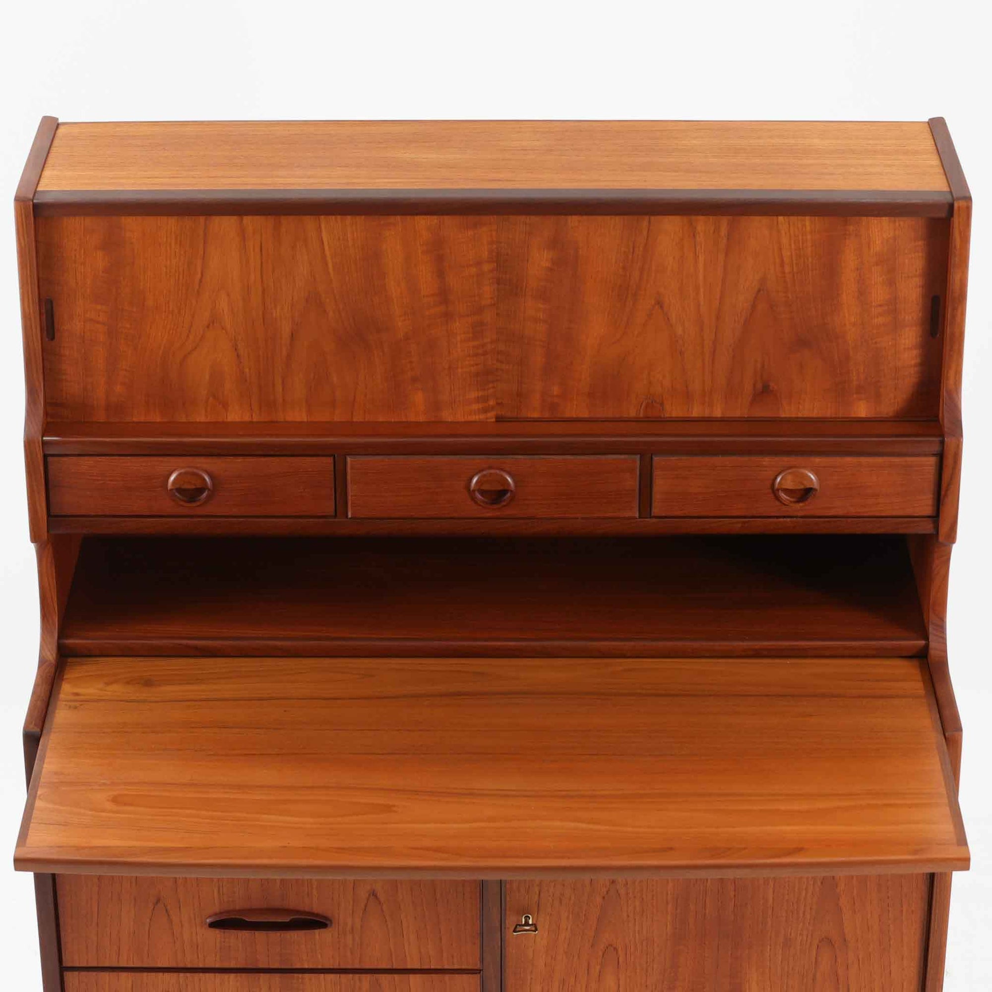 デンマーク製のビンテージライティングビューロです。チーク材を使用した温かみのある木肌と美しい木目が印象的で、北欧家具ならではの上質な存在感を放ちます。上部の引き戸収納や小引き出し、下部の引き出しとキャビネットを備え、機能的に整理できる実用的な設計が魅力。天板をデスクとして使えるため、書き物や作業スペースとしても活躍します。丸みを帯びたフォルムや細身の脚部が軽やかな印象を与え、経年により深みを増したチークの風合いがビンテージ家具ならではの味わいを楽しめる一台です。