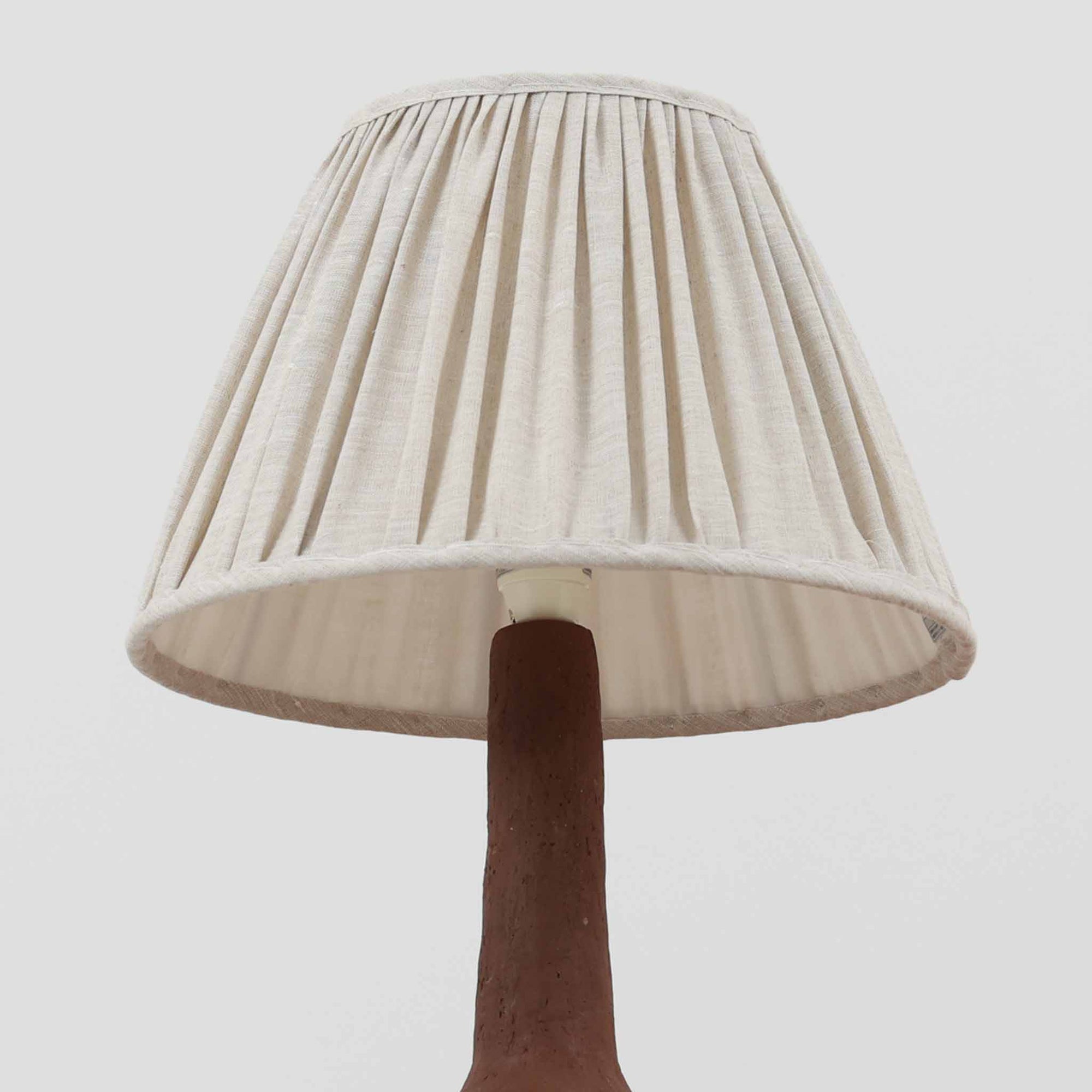 デンマーク製のテーブルランプは、高さ50cmと存在感のあるサイズが魅力の一点物ビンテージ品です。陶磁器ベースは下部に緑がかった釉薬を施し、上部は素地を生かしたマットな質感で仕上げられており、素材のコントラストがデザインの個性を際立たせています。プリーツ入りのリネンシェードを透す光はやわらかく広がり、リビングや寝室を温かみのある雰囲気に演出します。メーカー不詳・デザイナー不明ながら、Studio Potteryらしいクラフトマンシップを感じられる一点物の北欧ビンテージ品です。