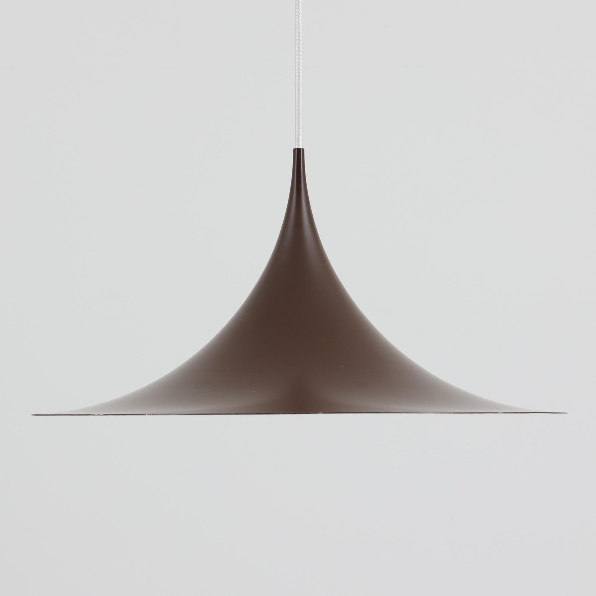 Claus BonderupとTorsten Thorupによるデザインのペンダントライト「Semi」は、Fog & Morup社から発表された北欧モダンを象徴する名作です。直径47cmのアルミシェードは美しい円錐を上下で切り取ったような独特のフォルムを持ち、光を下方向へ効率的に導きます。そのシャープでミニマルな造形は、空間にモダンな緊張感と優雅さをもたらし、ダイニングやリビングの中心を引き立てます。ビンテージならではの希少性と時を経た質感が一層の魅力を添え、北欧デザインの洗練を感じさせる一灯です。