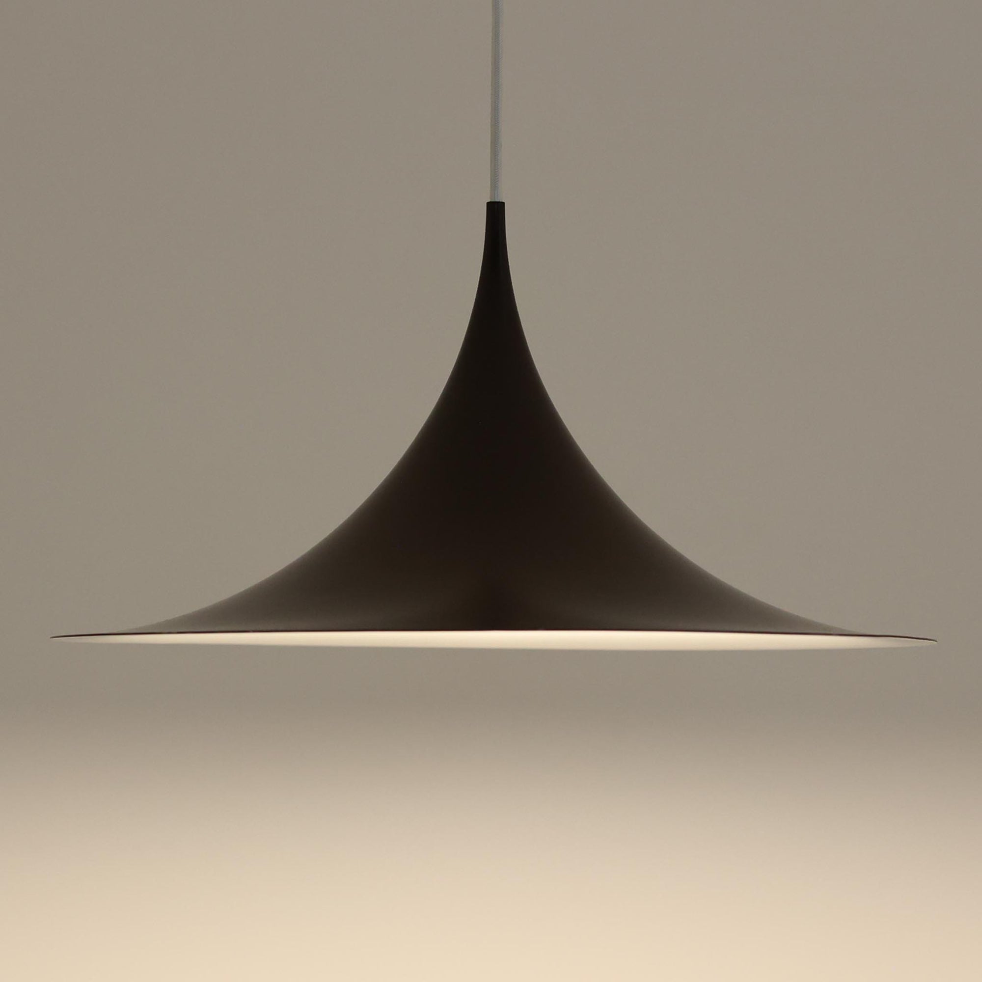 Claus BonderupとTorsten Thorupによるデザインのペンダントライト「Semi」は、Fog & Morup社から発表された北欧モダンを象徴する名作です。直径47cmのアルミシェードは美しい円錐を上下で切り取ったような独特のフォルムを持ち、光を下方向へ効率的に導きます。そのシャープでミニマルな造形は、空間にモダンな緊張感と優雅さをもたらし、ダイニングやリビングの中心を引き立てます。ビンテージならではの希少性と時を経た質感が一層の魅力を添え、北欧デザインの洗練を感じさせる一灯です。