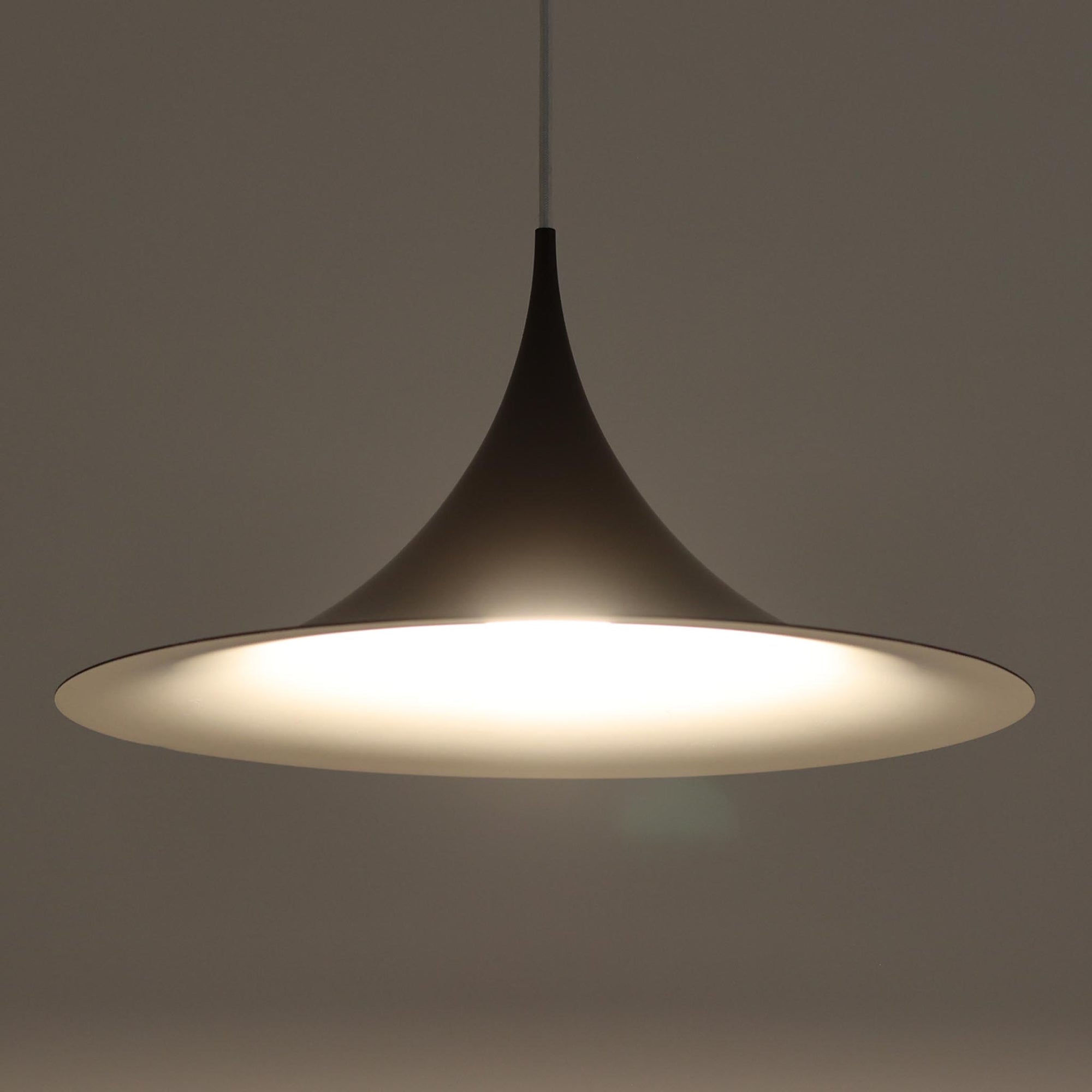 Claus BonderupとTorsten Thorupによるデザインのペンダントライト「Semi」は、Fog &amp; Morup社から発表された北欧モダンを象徴する名作です。直径47cmのアルミシェードは美しい円錐を上下で切り取ったような独特のフォルムを持ち、光を下方向へ効率的に導きます。そのシャープでミニマルな造形は、空間にモダンな緊張感と優雅さをもたらし、ダイニングやリビングの中心を引き立てます。ビンテージならではの希少性と時を経た質感が一層の魅力を添え、北欧デザインの洗練を感じさせる一灯です。