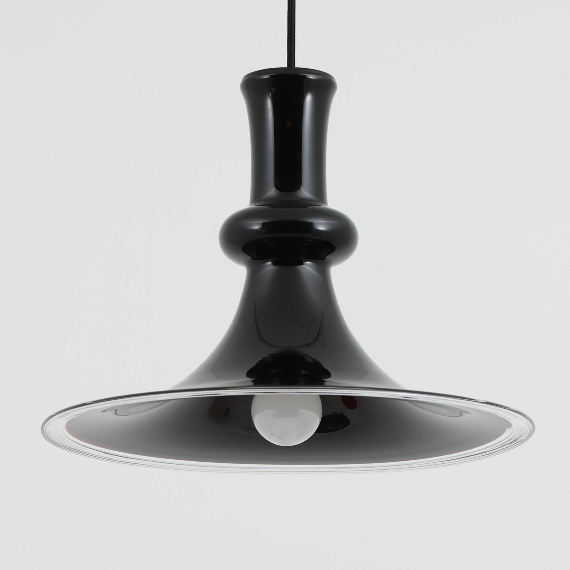 Michael BangがHolmegaard社のためにデザインしたペンダントライト「Etude」は、直径38cmのガラスシェードが放つ透明感と深みのある輝きが魅力です。ボトルのような有機的なフォルムに広がるフレア形状は、光を効果的に拡散しつつ下方をしっかりと照らし、点灯時にはガラス内部に幻想的な光の表情を生み出します。ダイニングやリビングの中心に映える存在感を持ち、インテリアに洗練されたアクセントを添えます。ビンテージならではの希少性とHolmegaardの職人技が息づく逸品です。